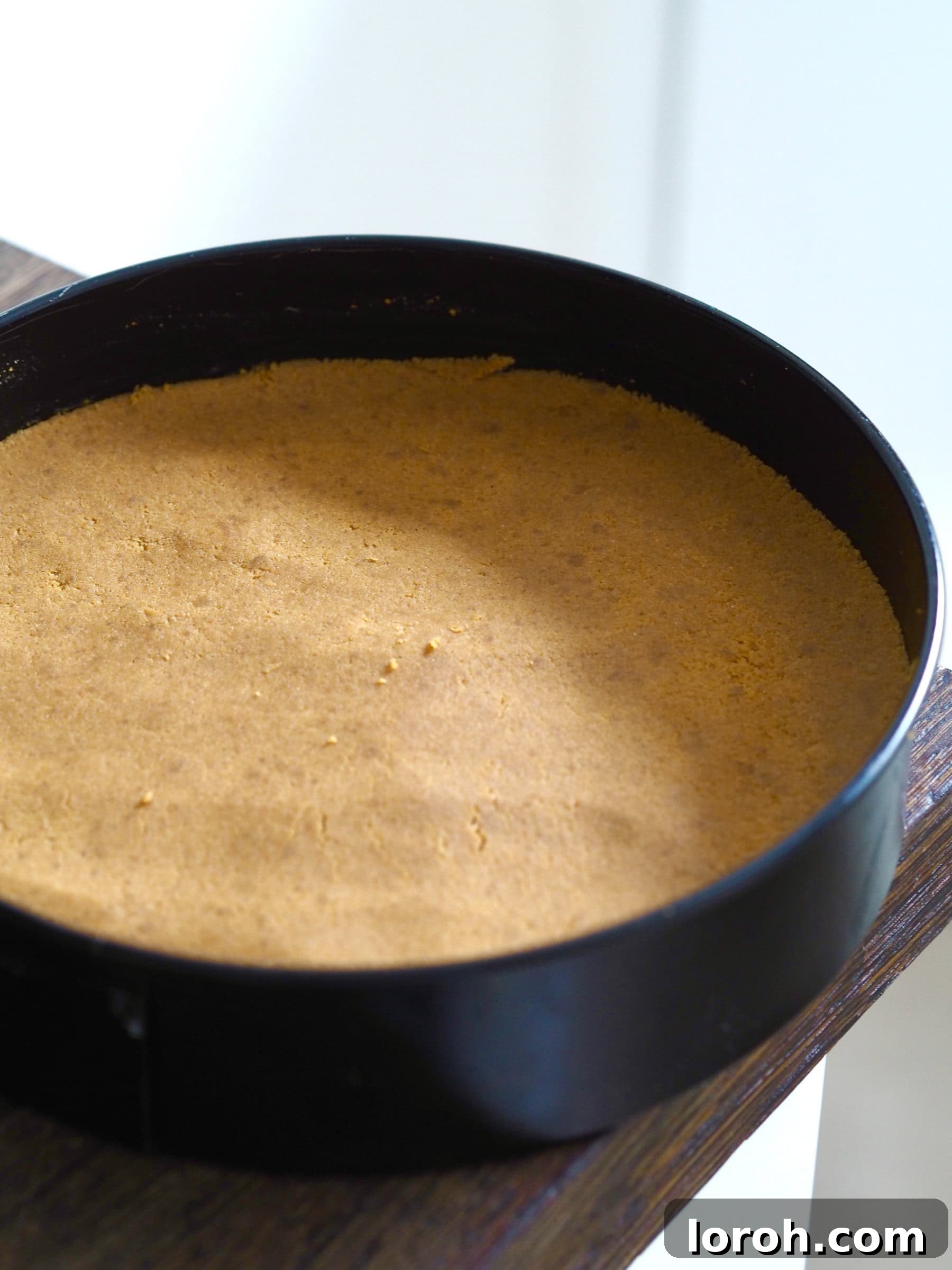 The biscuit base firmly pressed into a springform tin, creating an even layer for the cheesecake.
