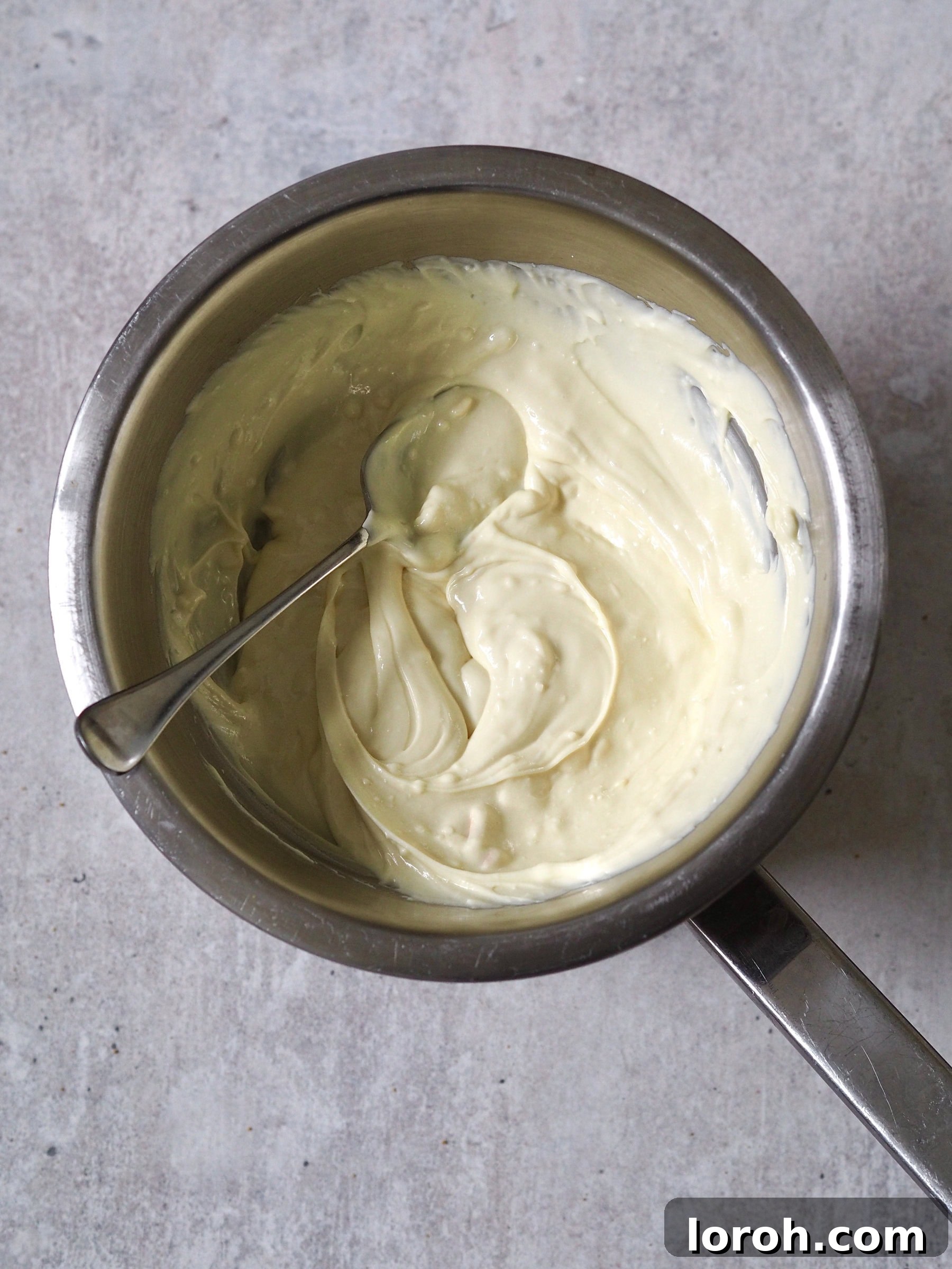 Smooth, melted white chocolate ganache, cooled to room temperature and ready to be incorporated into the cheesecake filling.