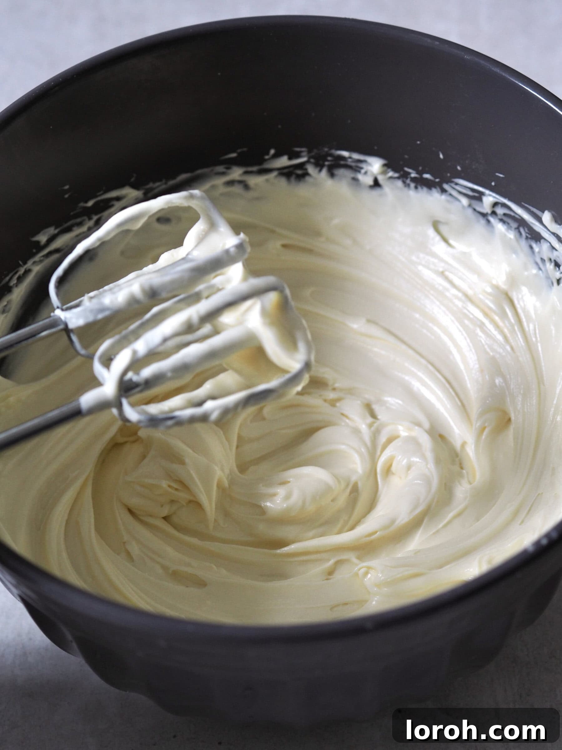 The creamy cheesecake filling, a blend of whipped cream cheese, double cream, melted white chocolate, and passion fruit juice, showing its fluffy texture.