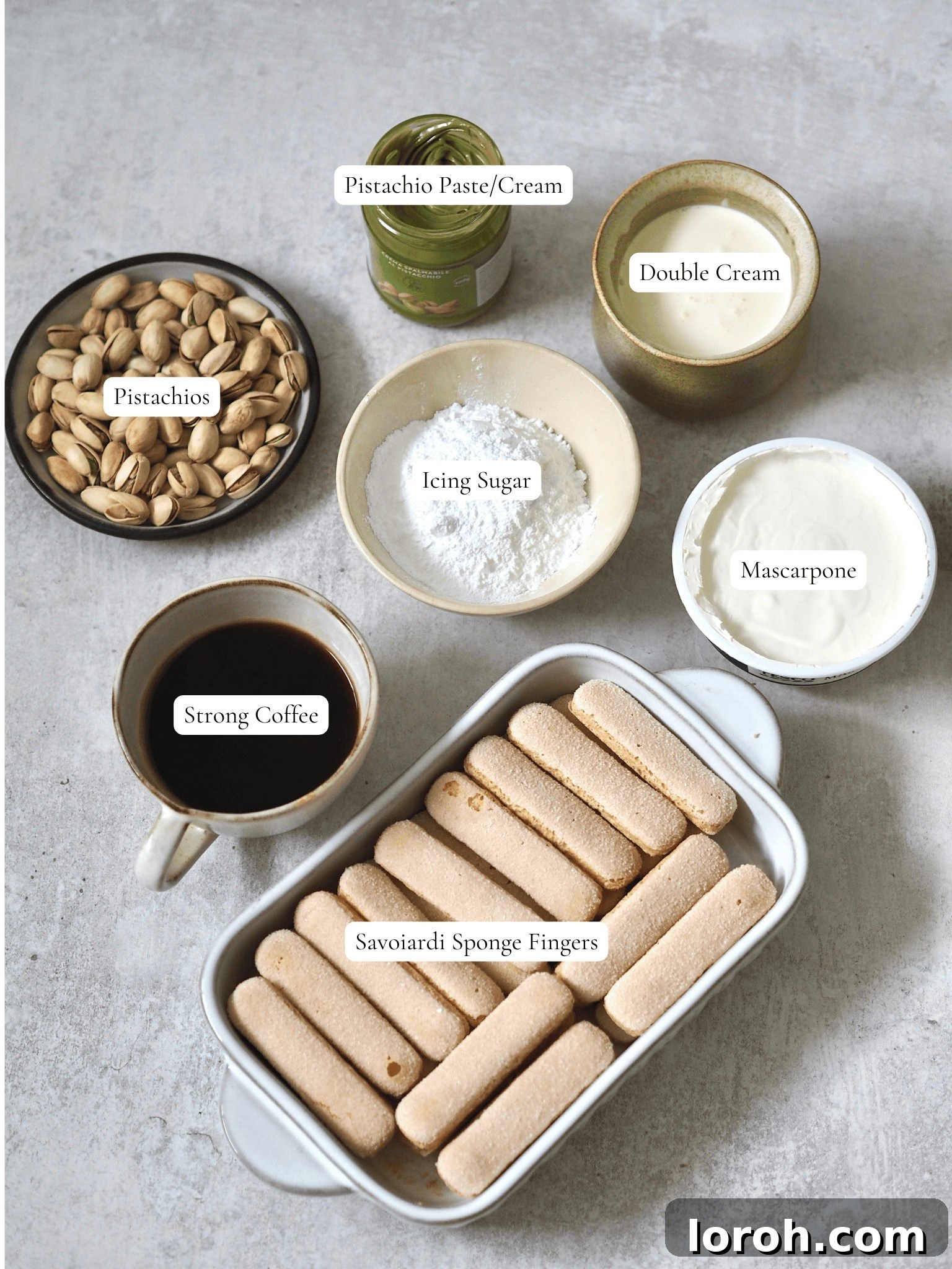 Labelled ingredients for pistachio tiramisu laid out on a surface.