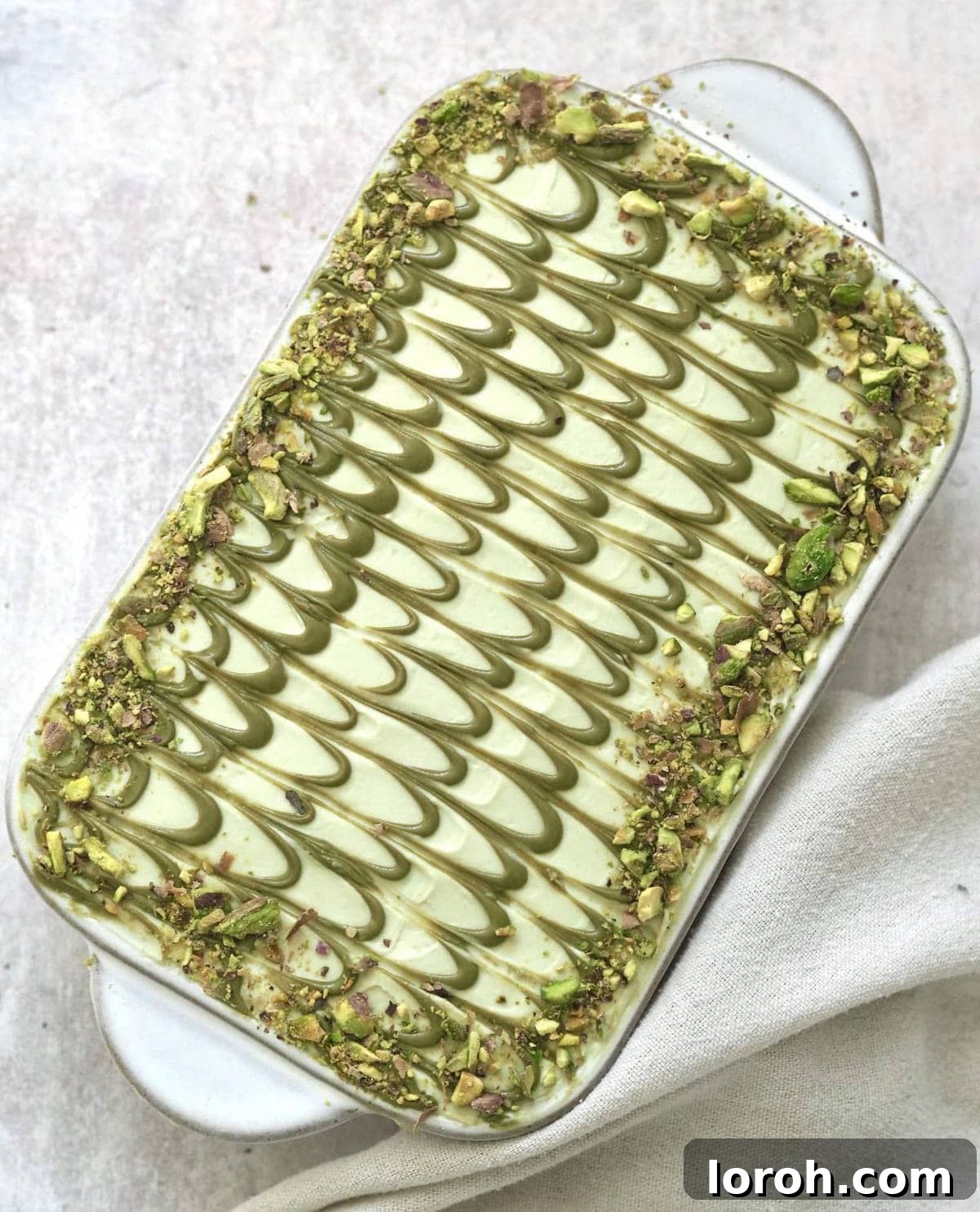 A pristine white dish filled with beautifully layered pistachio tiramisu, ready for serving.