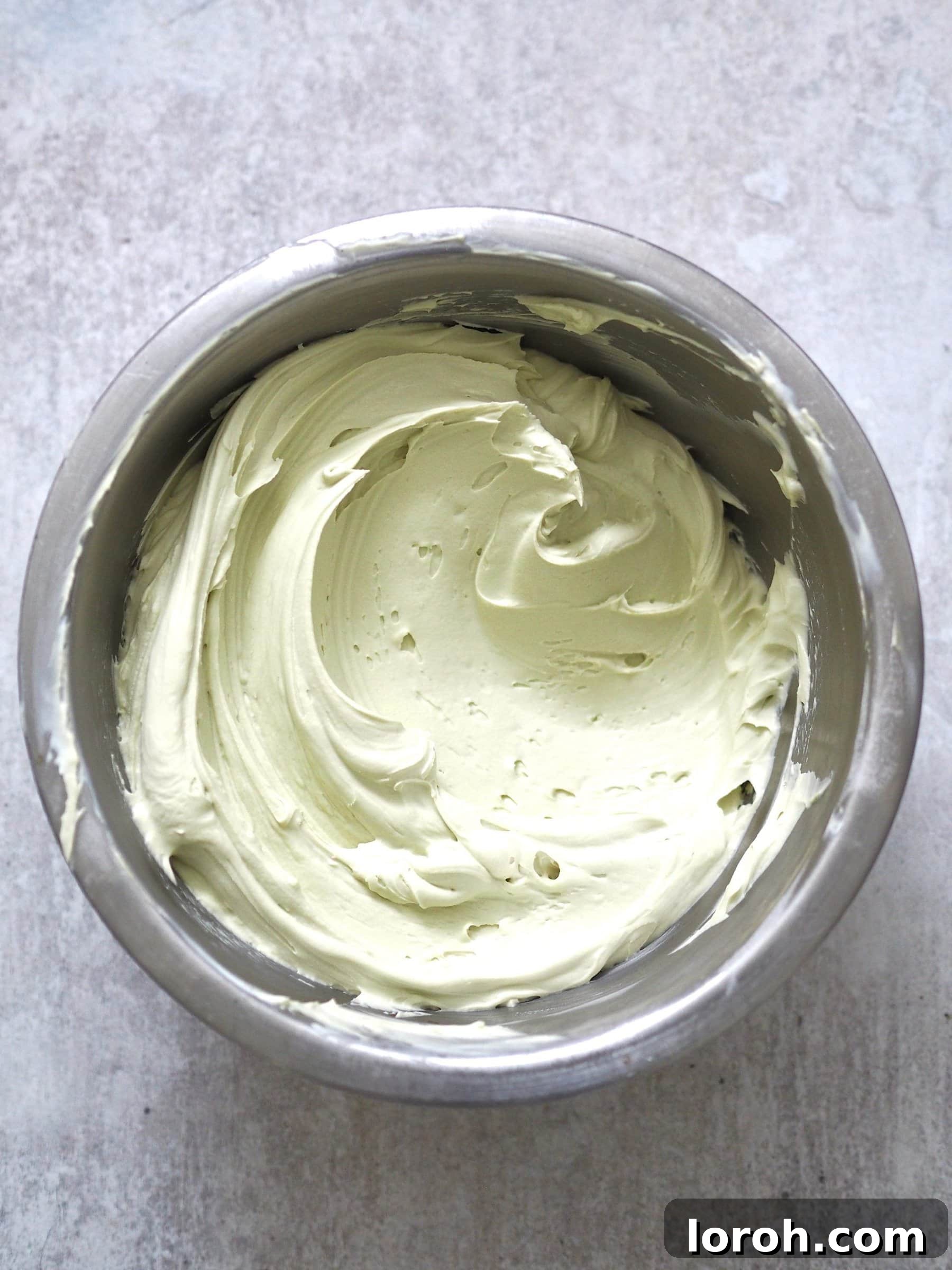Freshly whipped pistachio cream in a metal mixing bowl.