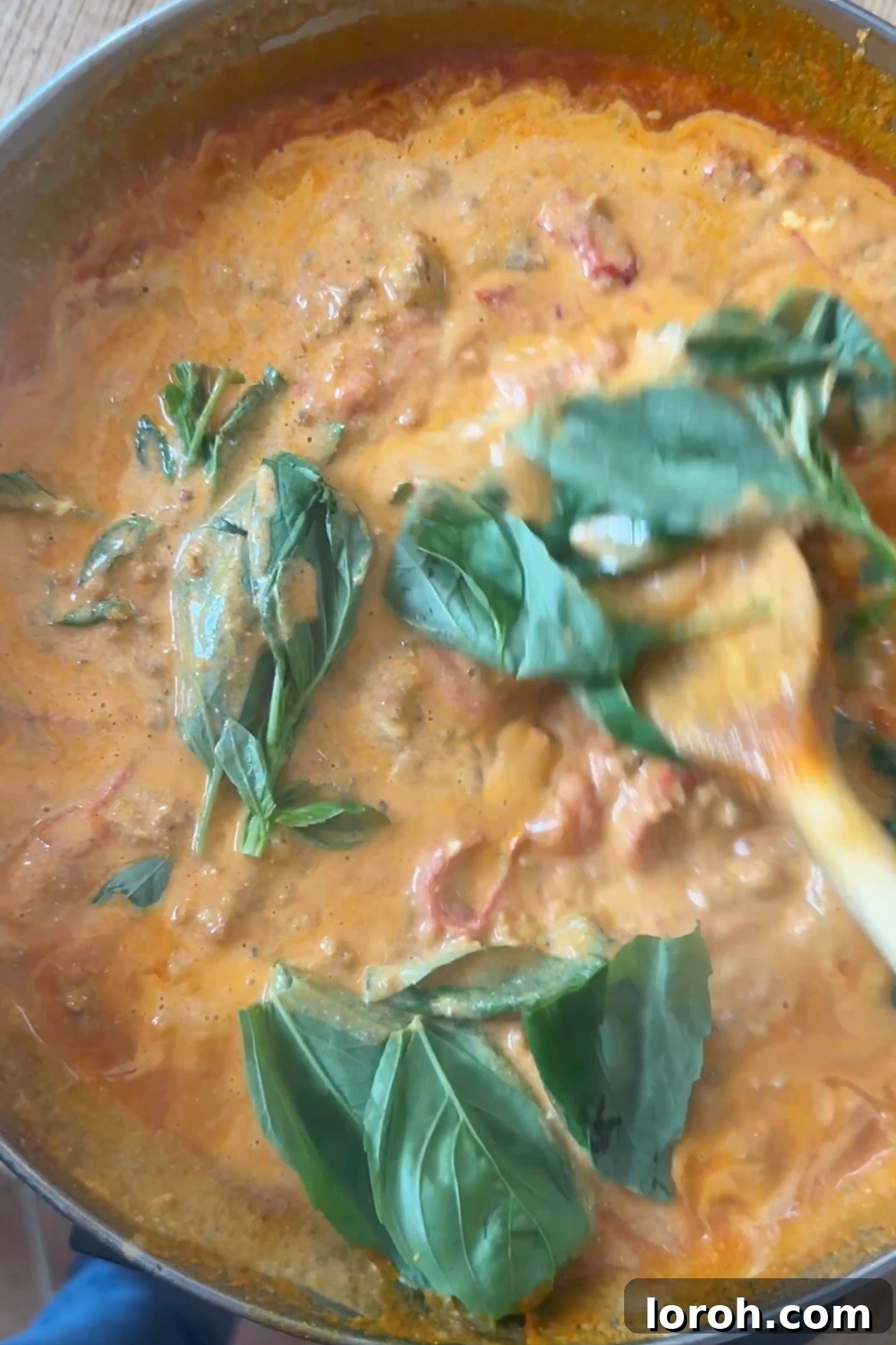 Fresh basil leaves being added to the creamy Nduja pasta sauce.
