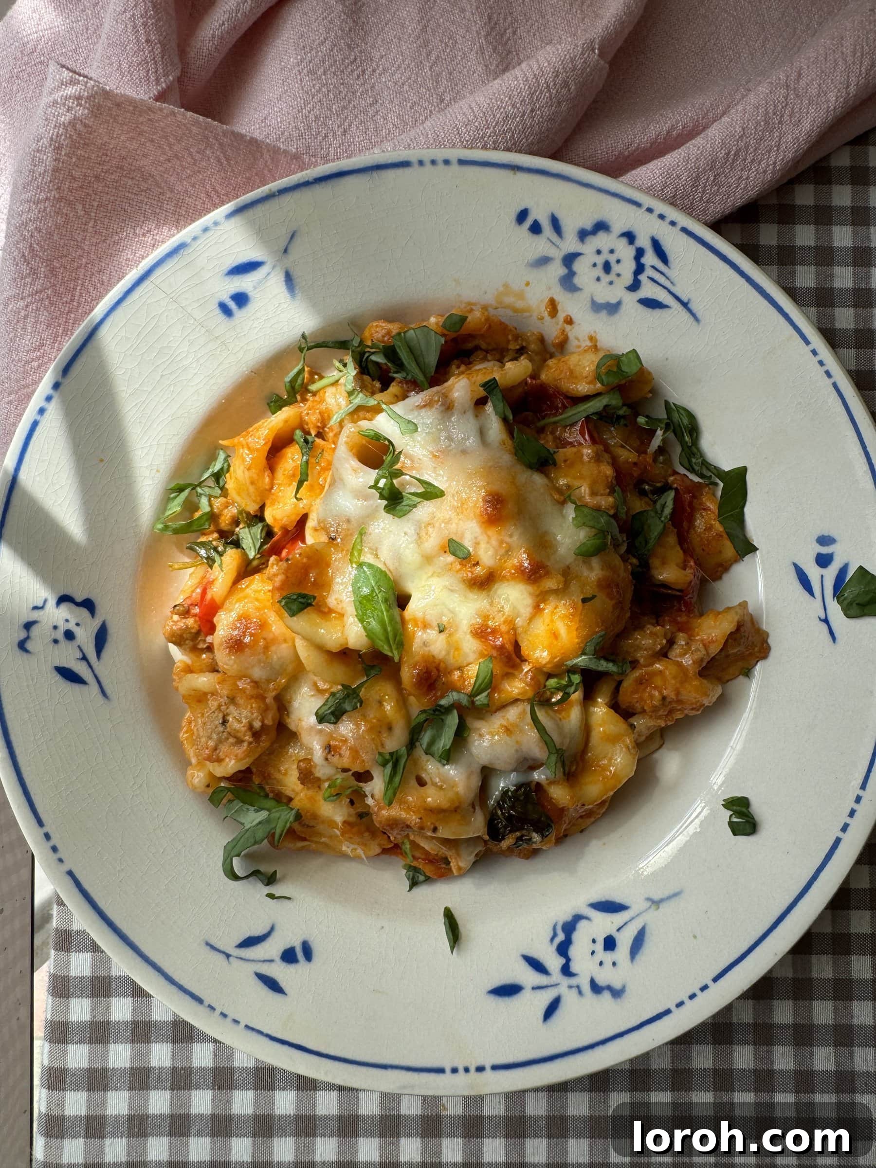 A comforting bowl of Nduja and Sausage Pasta Bake with melted cheese and fresh basil