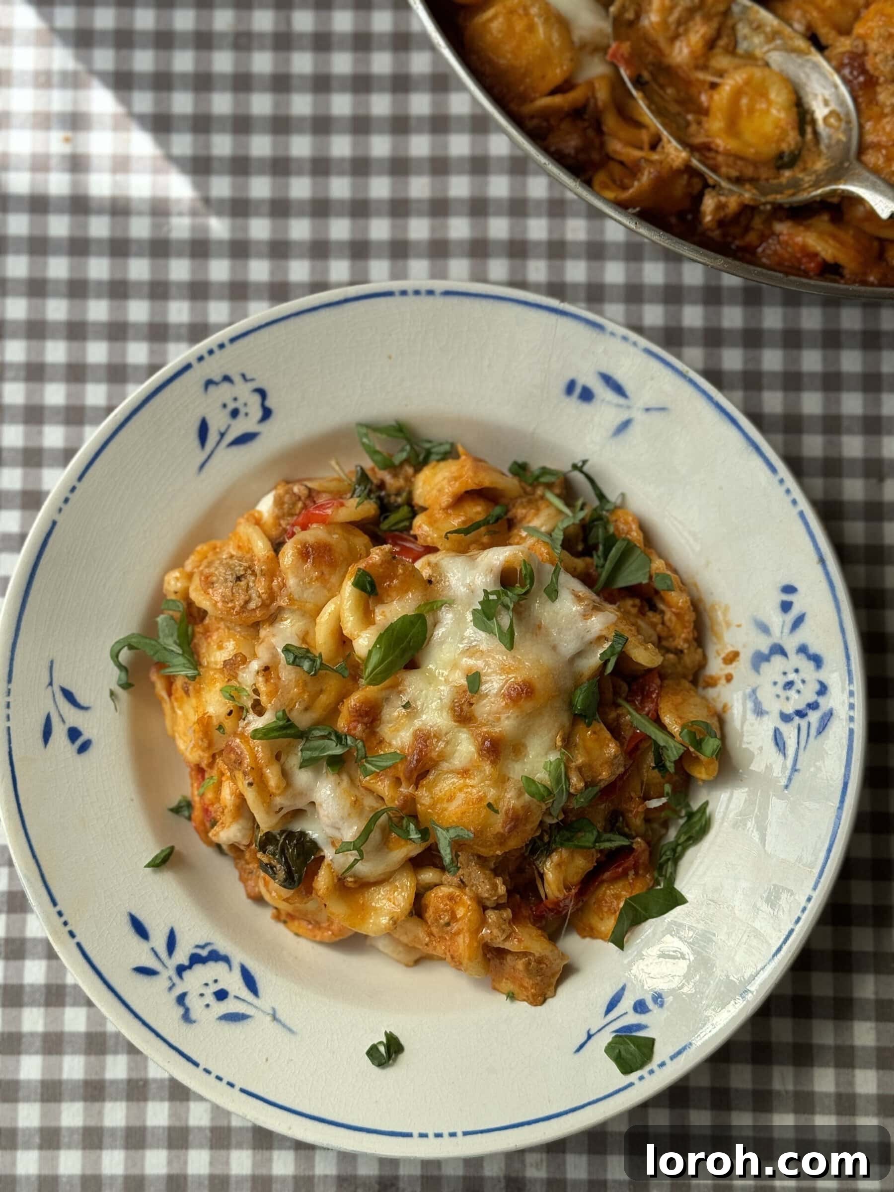 Close-up of fresh ingredients for Nduja and Sausage Pasta Bake, including cherry tomatoes, basil, and nduja
