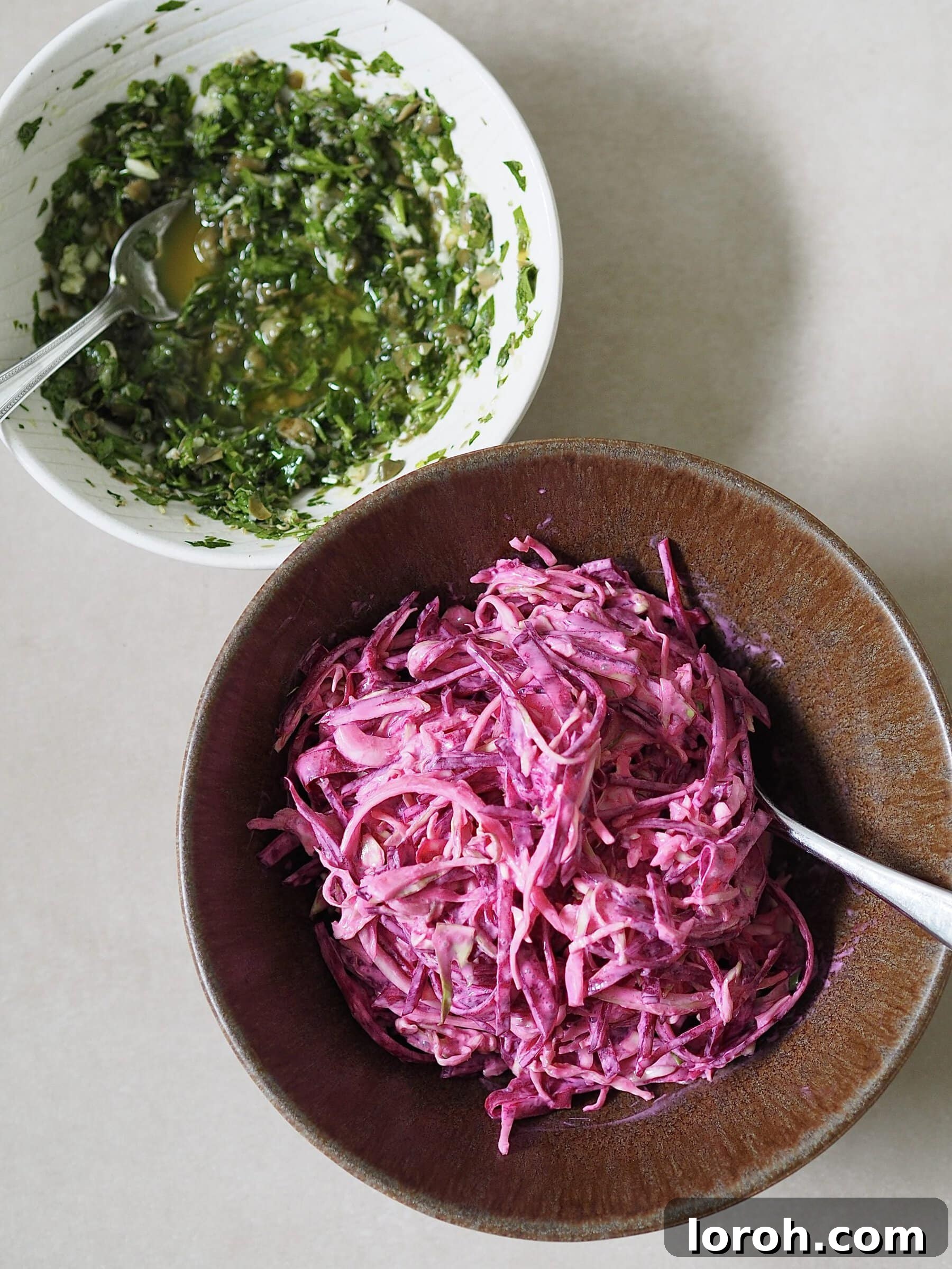 Separate bowls of green salsa verde and pink yogurt slaw on a white countertop, ready for serving.