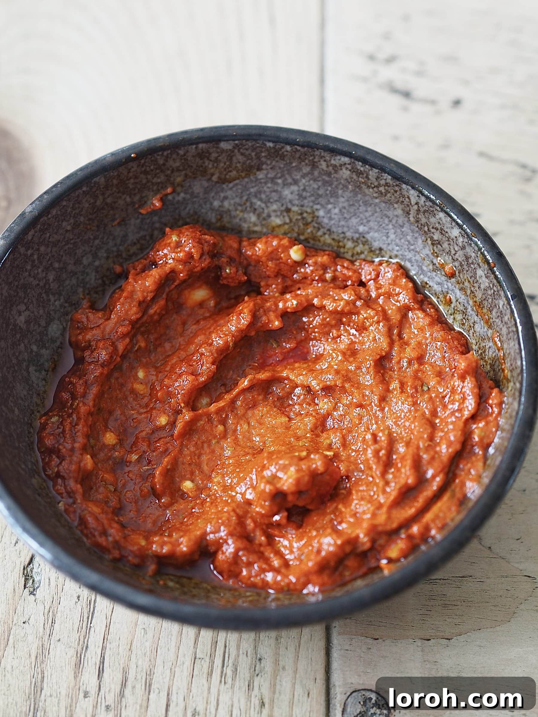 Zesty Peri Peri Chicken with Golden Potato Wedges 4 Homemade peri peri sauce in a black bowl on a wooden table.
