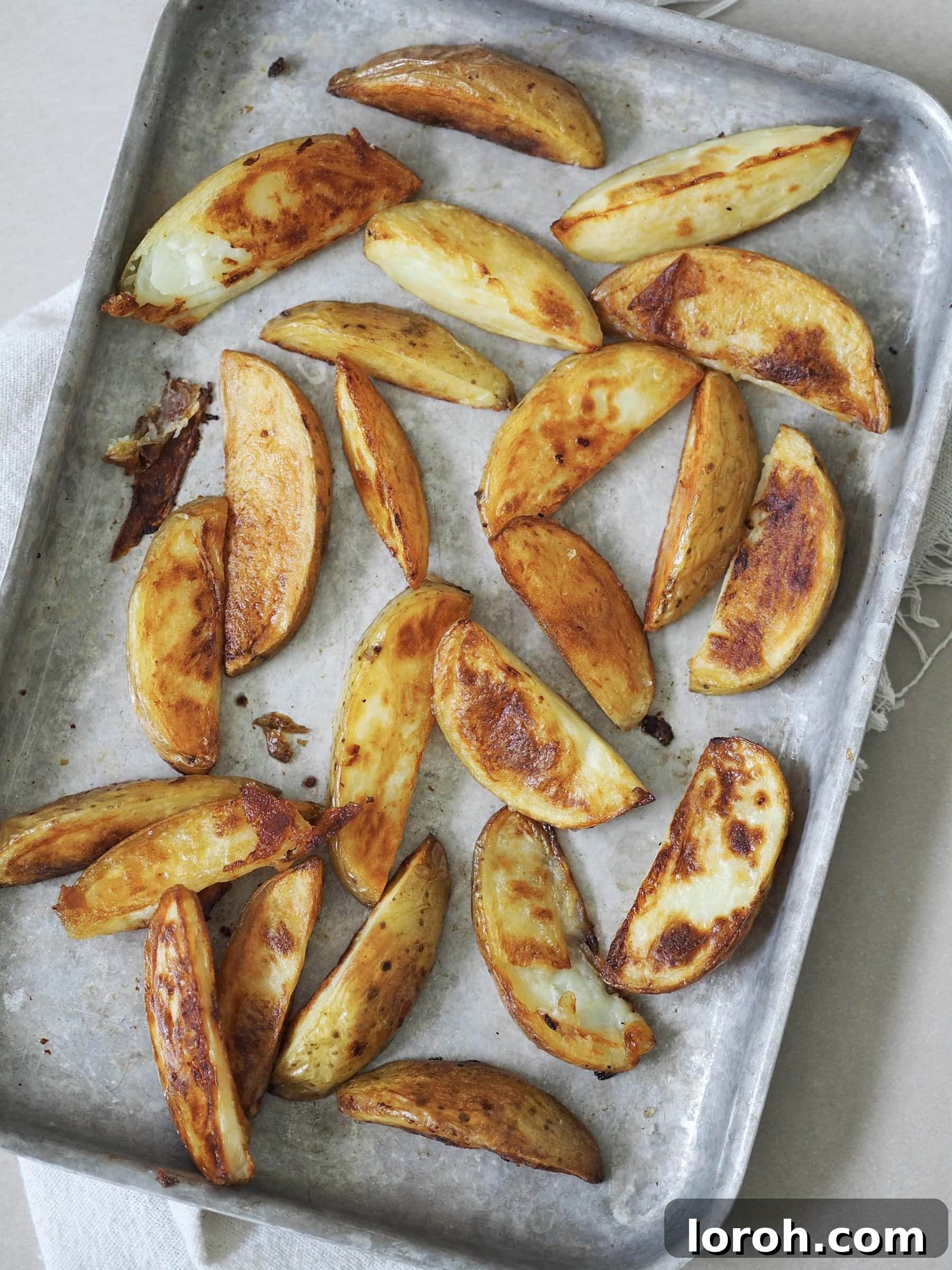 Zesty Peri Peri Chicken with Golden Potato Wedges 8 Crispy roasted potato wedges on a metal baking tray.