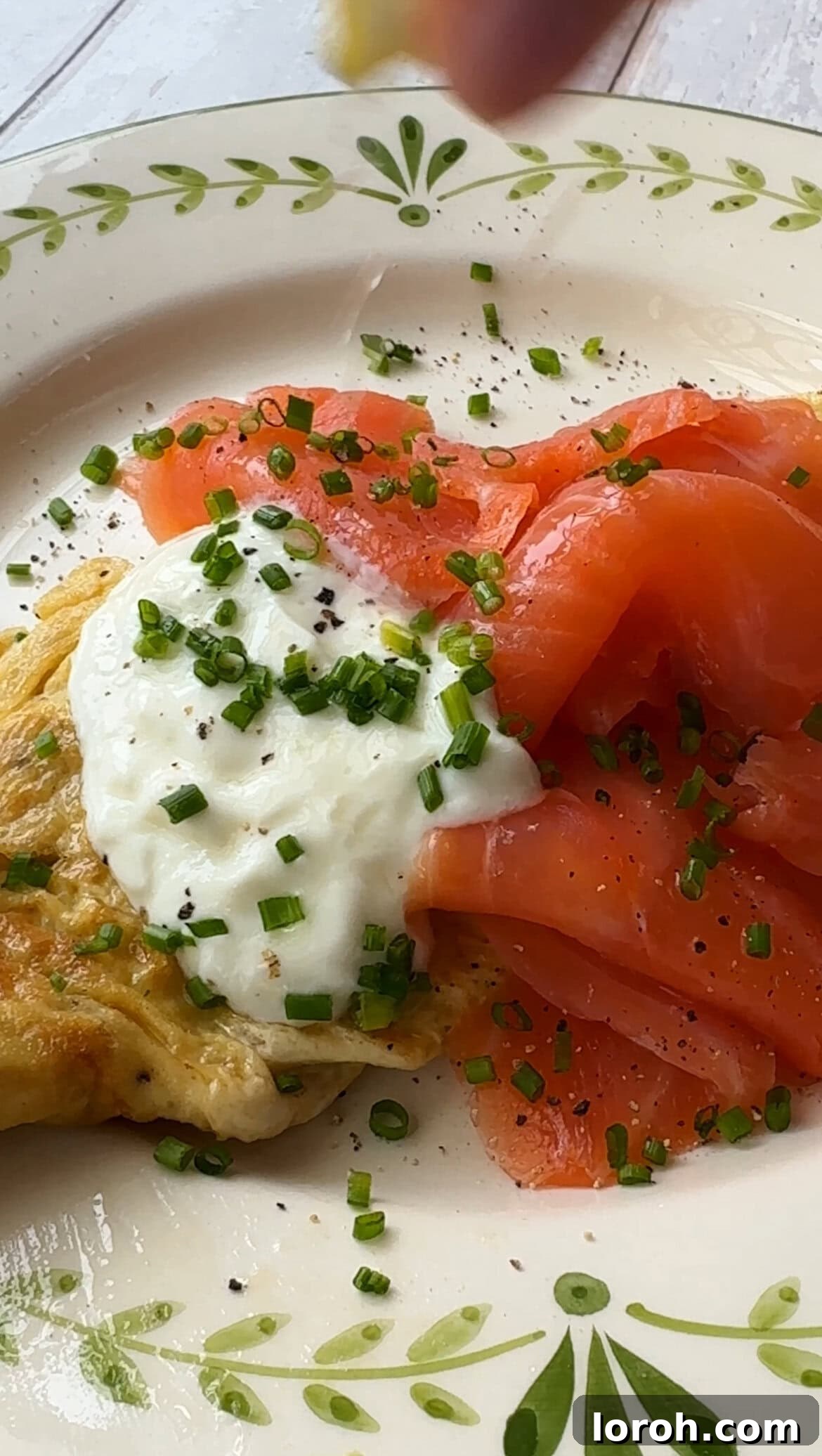 Step six: Topping the omelette with smoked salmon, crème fraîche, and chives.