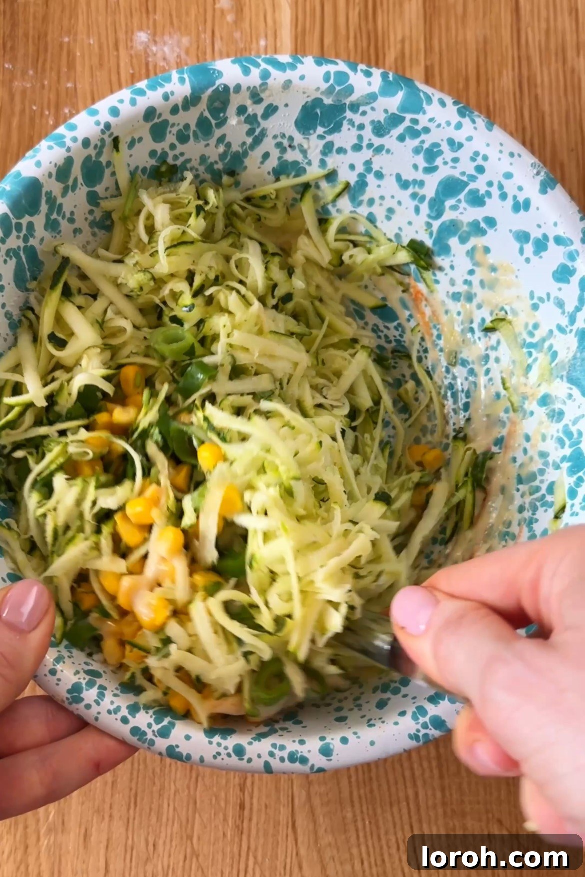 Adding grated courgette, sweetcorn, spring onions, and coriander to the batter