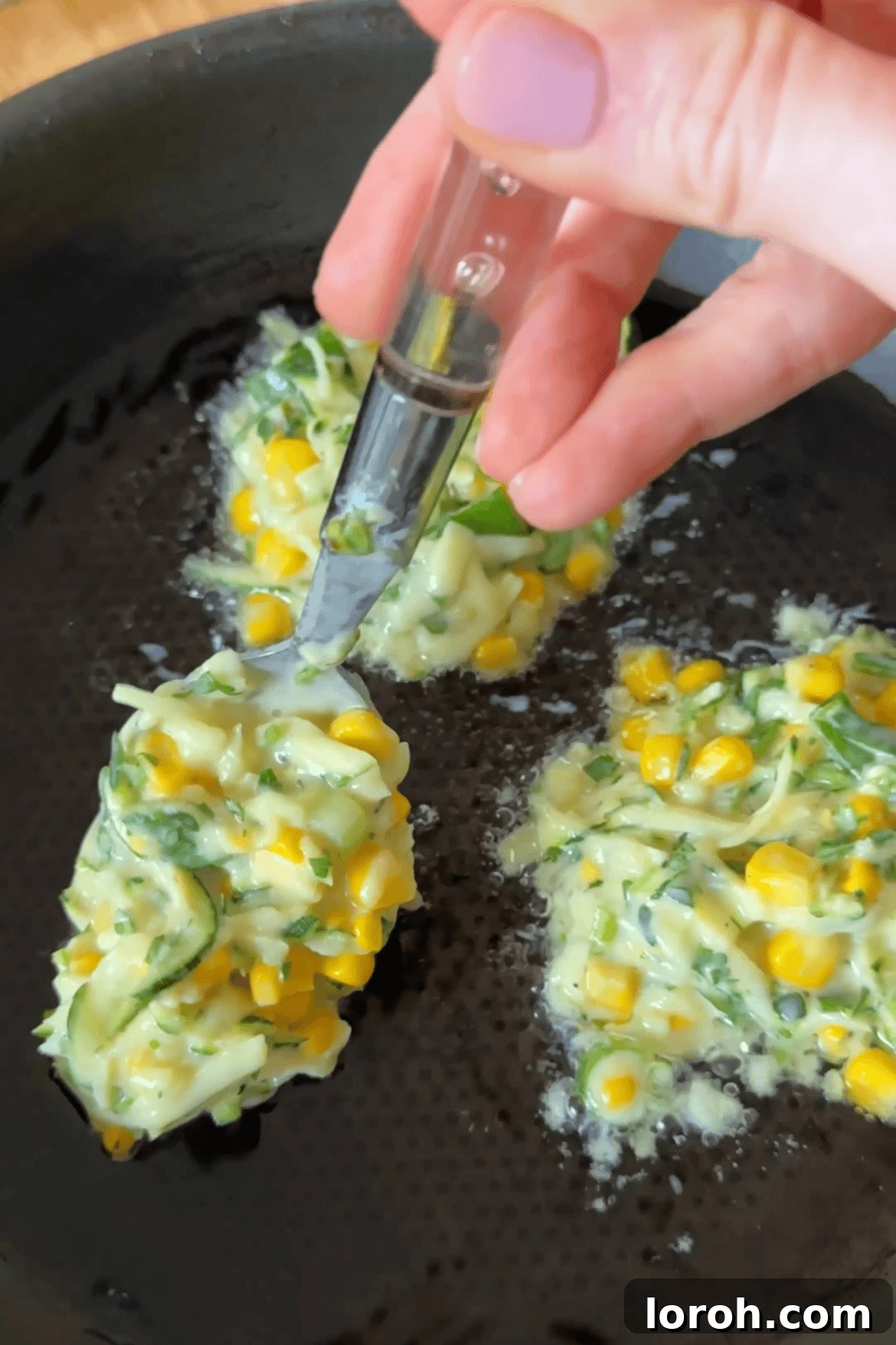 Frying courgette and corn fritters in a non-stick pan