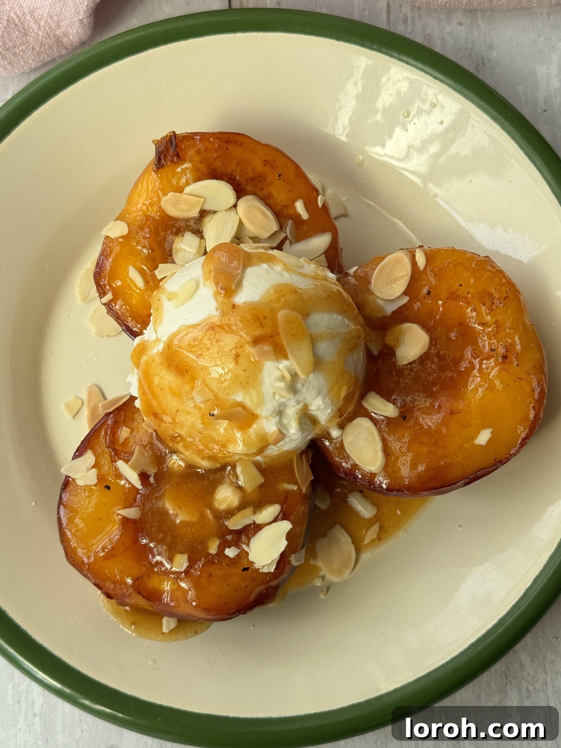 Peaches and cream served on a white plate with a green rim, showcasing the golden caramelized peaches and dollops of cream.