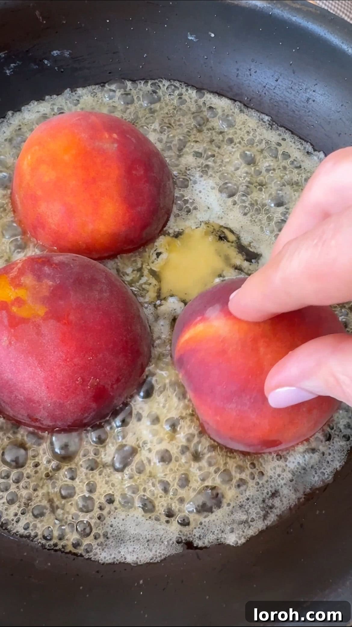 Frying peach halves cut-side down in the brown butter caramel.