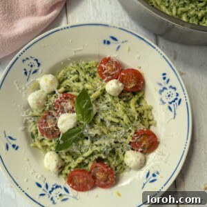 A beautifully plated bowl of Pasta al Pesto with fresh basil, mozzarella, and cherry tomatoes.