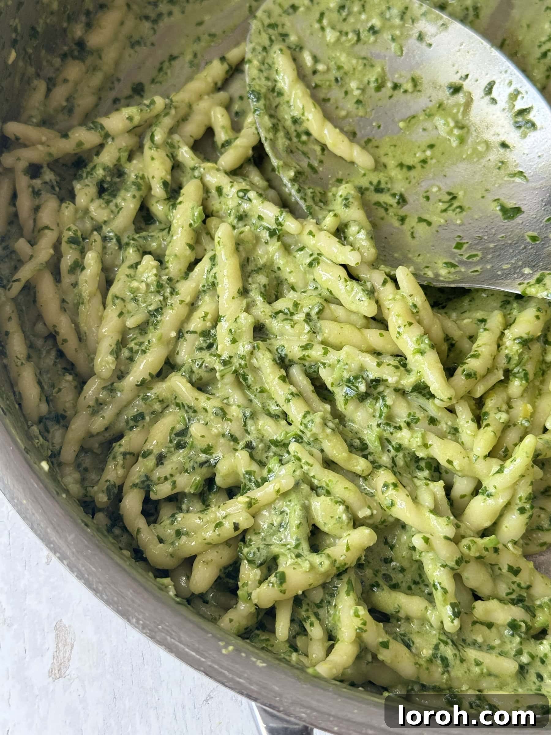 Pesto pasta cooking in a steel pan, ready to be served.
