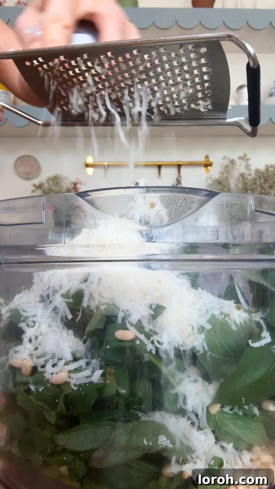 A generous amount of grated Parmesan cheese being added to the food processor.