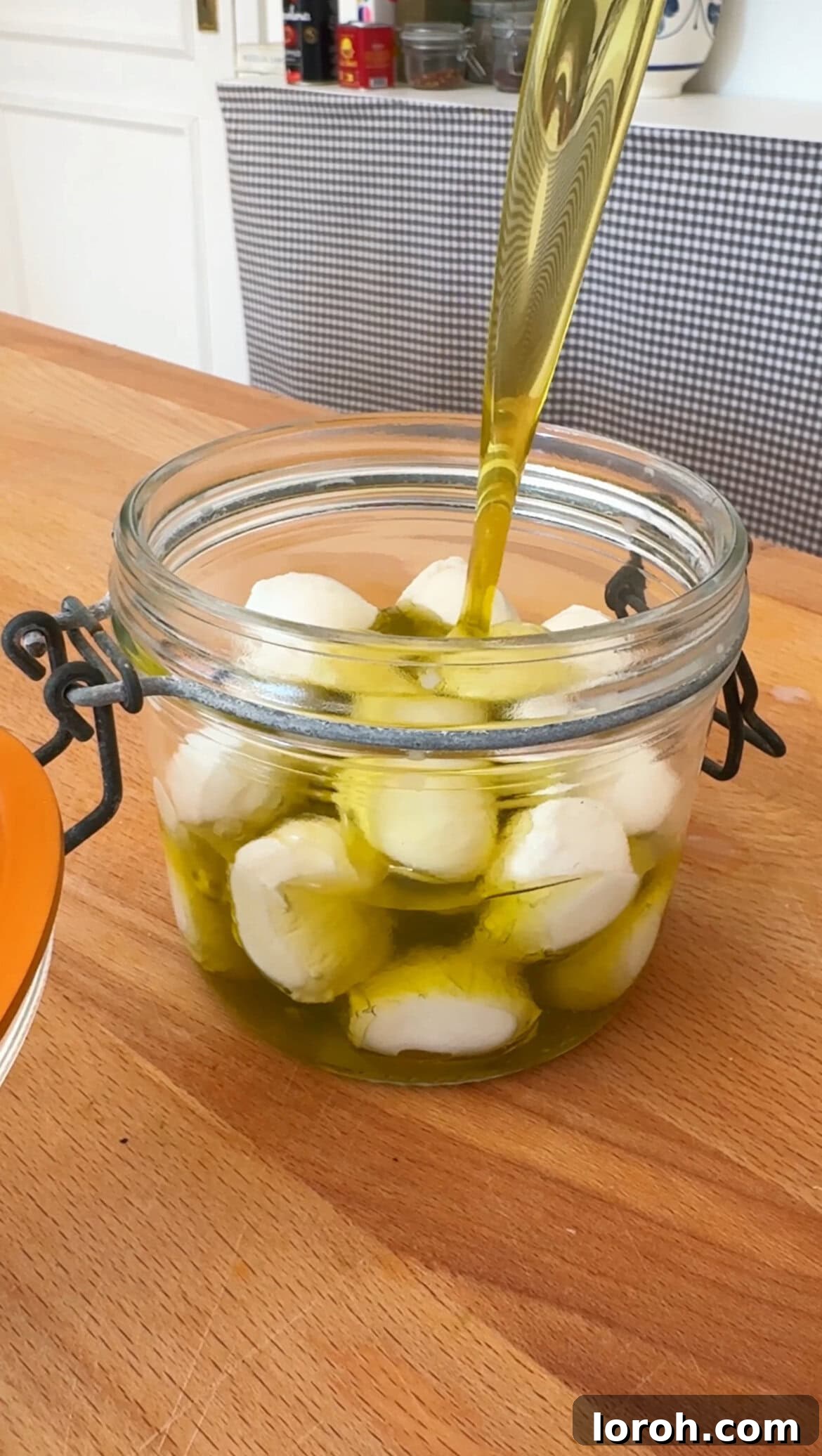 Marinated Mozzarella Bites 4 pouring olive oil on mozzarella balls in a jar
