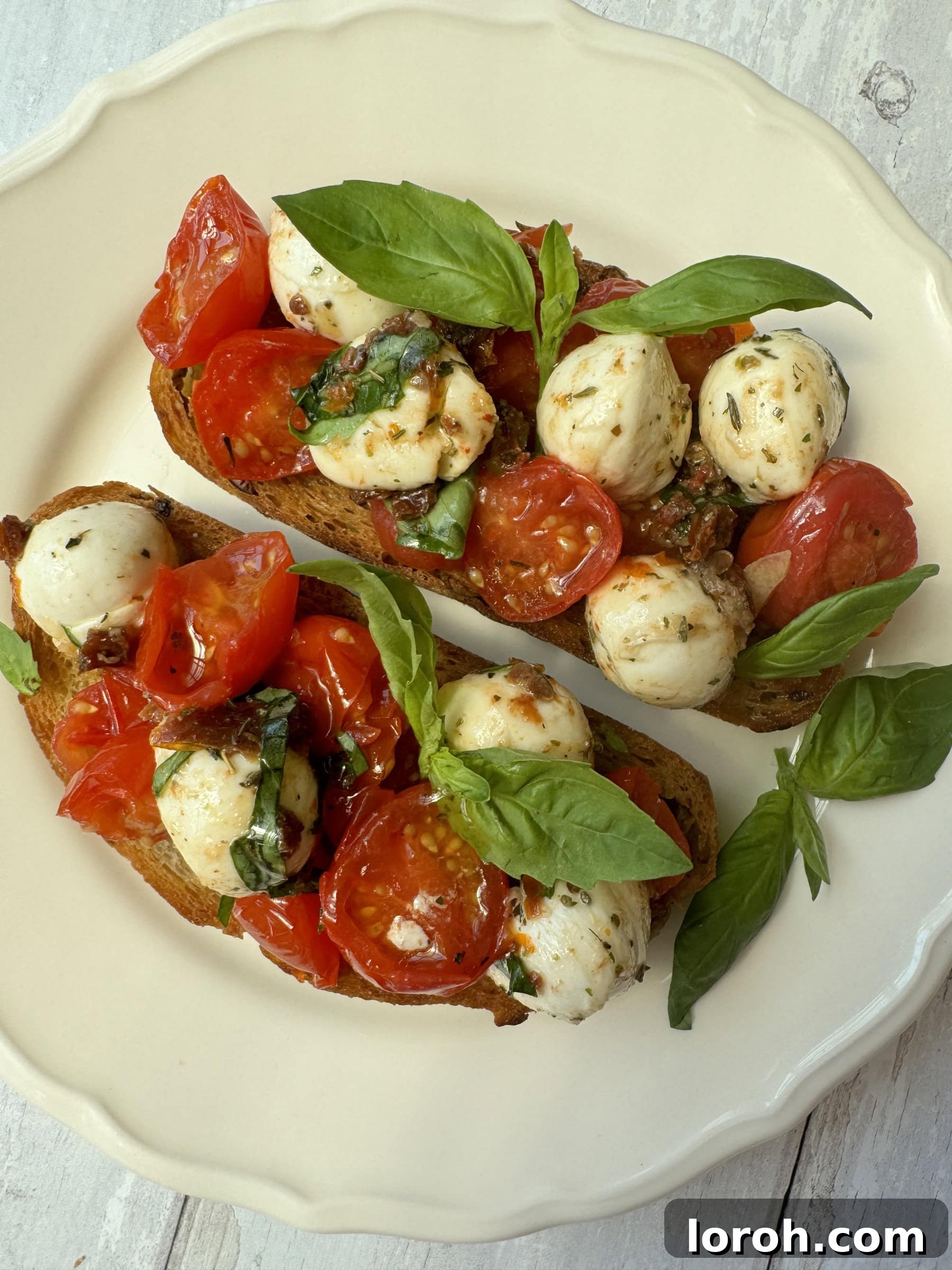 Marinated Mozzarella Bites 8 marinated mozzarella ball crostini on white plate, garnished with basil