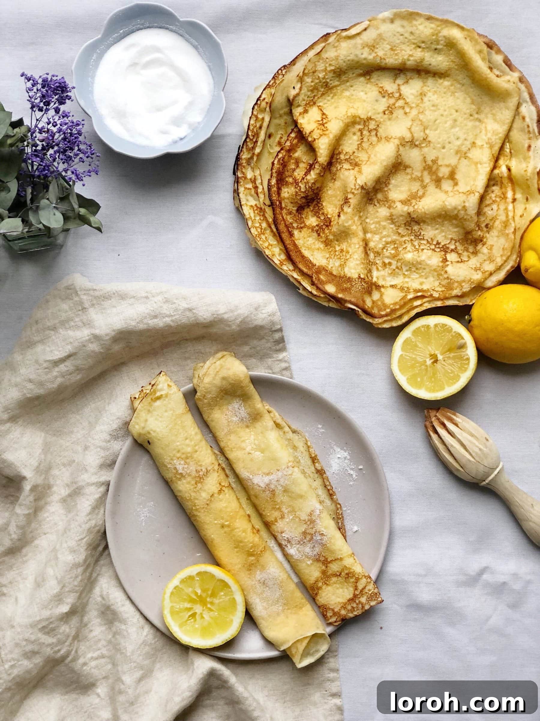 Classic British Pancakes For Every Occasion 2 A stack of perfectly golden British pancakes on a plate, garnished with fresh lemon halves, ready to be enjoyed.