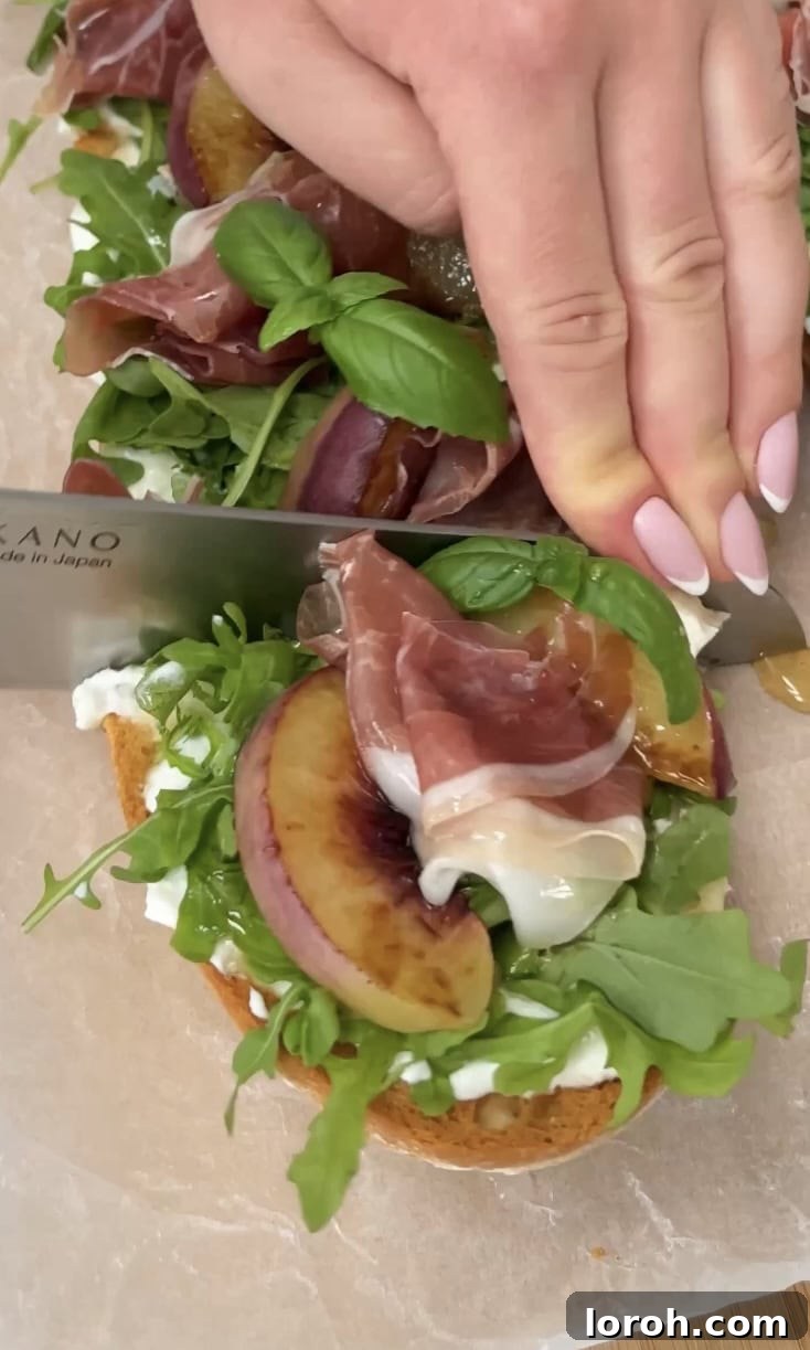 slicing peach burrata ciabatta. A knife slicing the finished grilled peach and burrata ciabatta into perfect serving portions on a wooden board.