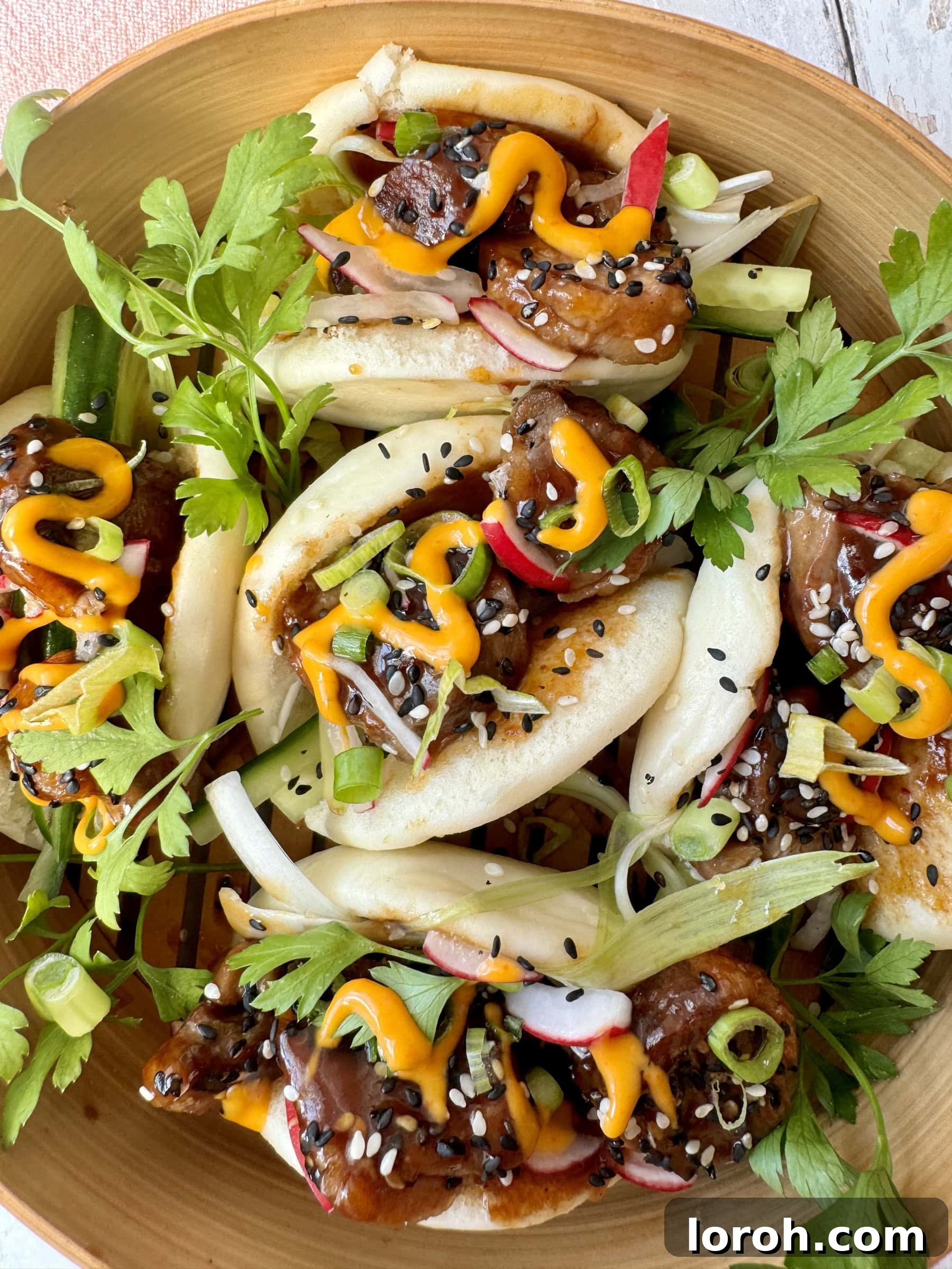 Peking Duck Bao Pockets 2 A vibrant plate of freshly prepared duck bao buns, showcasing crispy duck, fresh vegetables, and a creamy sriracha drizzle.