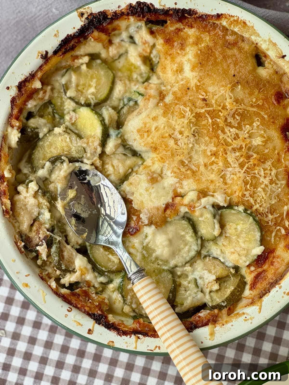 Golden-brown Gratin de Courgettes served in an elegant enamel baking dish, showcasing its crispy top and creamy interior, ready to be enjoyed.