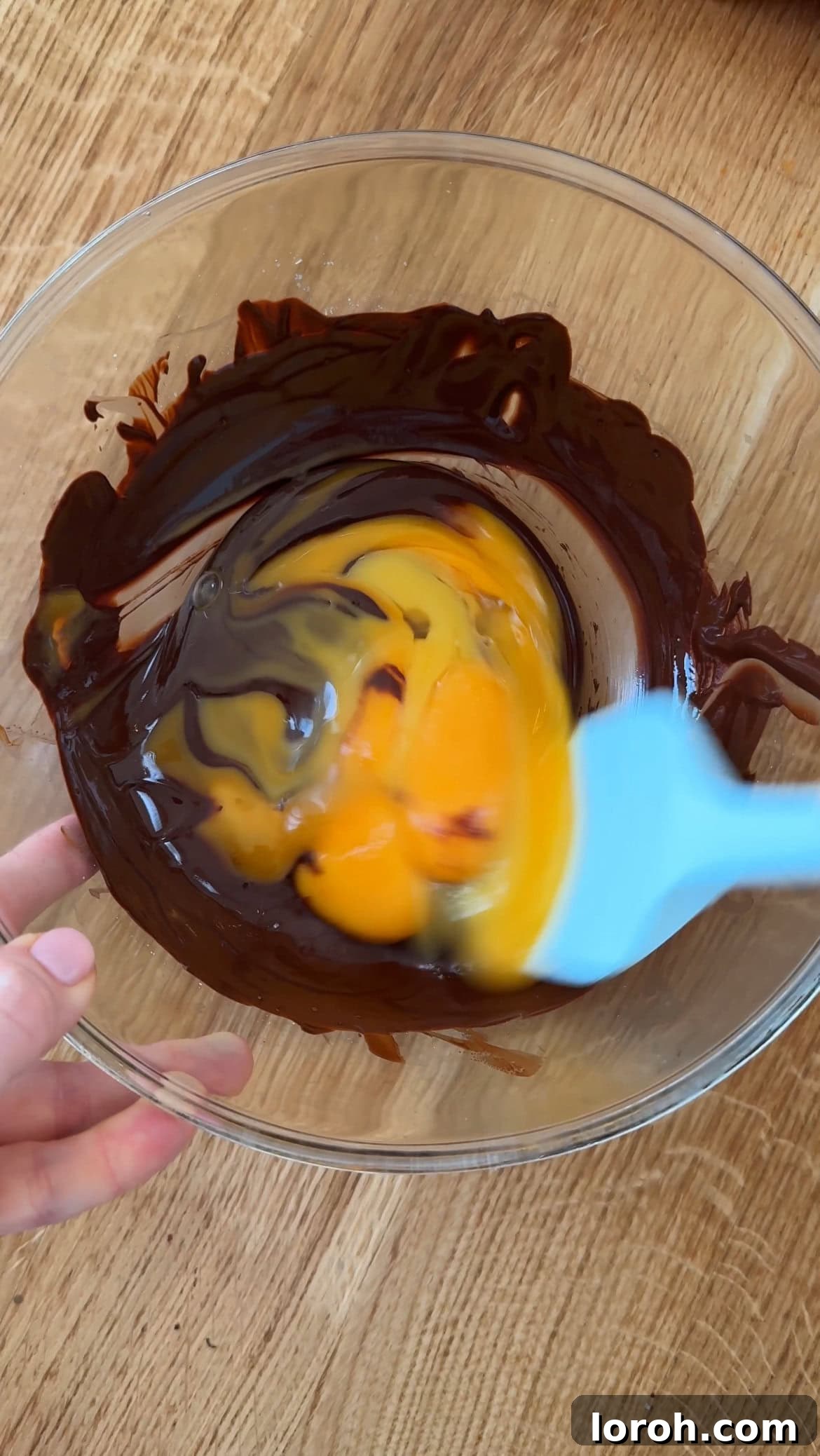 Step two: Adding egg yolks to melted chocolate and mixing until glossy.