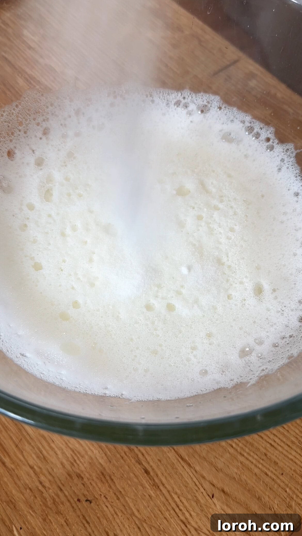 Step three: Whisking egg whites to soft peaks, then adding sugar for glossy meringue.