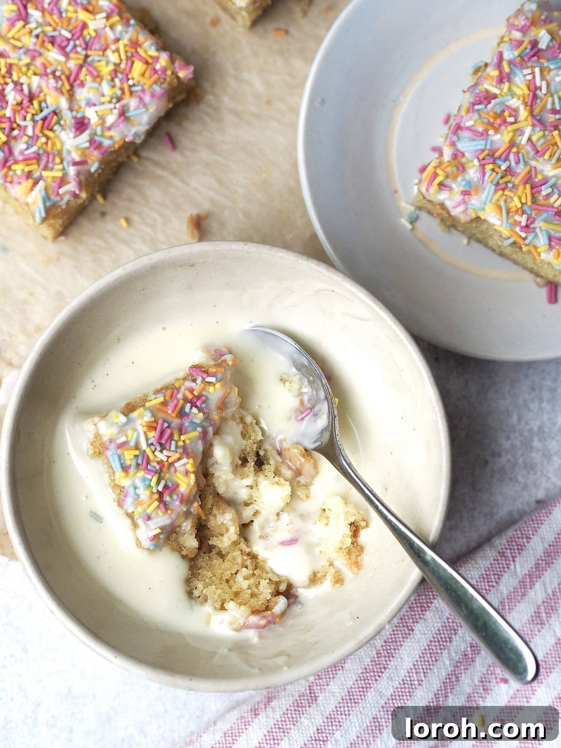 Classic Sprinkle Sponge with Golden Custard 5 A generous bowl of school dinner sponge cake topped with rainbow sprinkles, alongside a smaller bowl of warm, creamy custard, ready to be enjoyed.