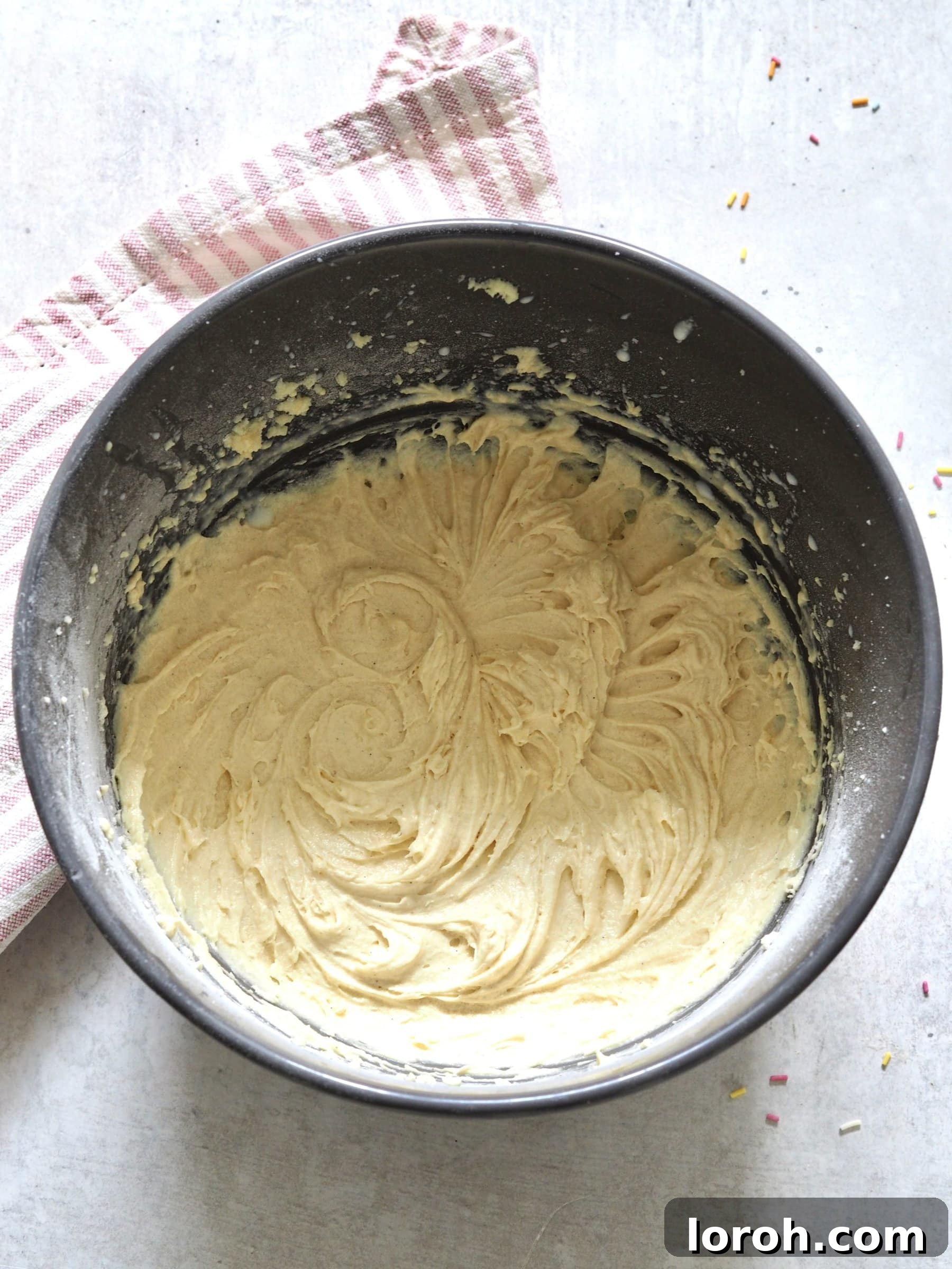 Classic Sprinkle Sponge with Golden Custard 7 Smooth, well-mixed cake batter resting in a metal bowl, showcasing its readiness for baking.