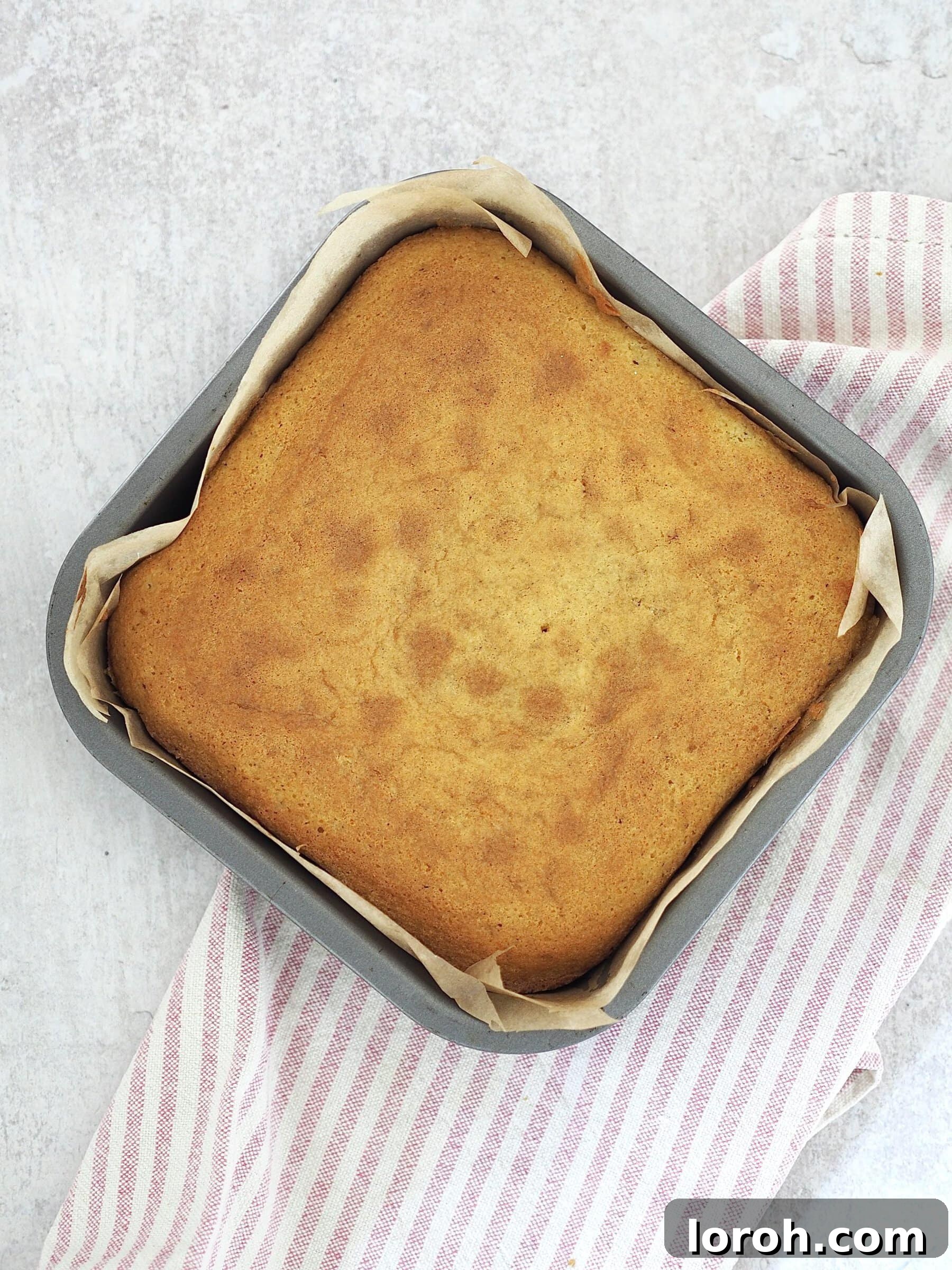 Classic Sprinkle Sponge with Golden Custard 8 A freshly baked, golden sponge cake resting within its lined tin, having just been removed from the oven.