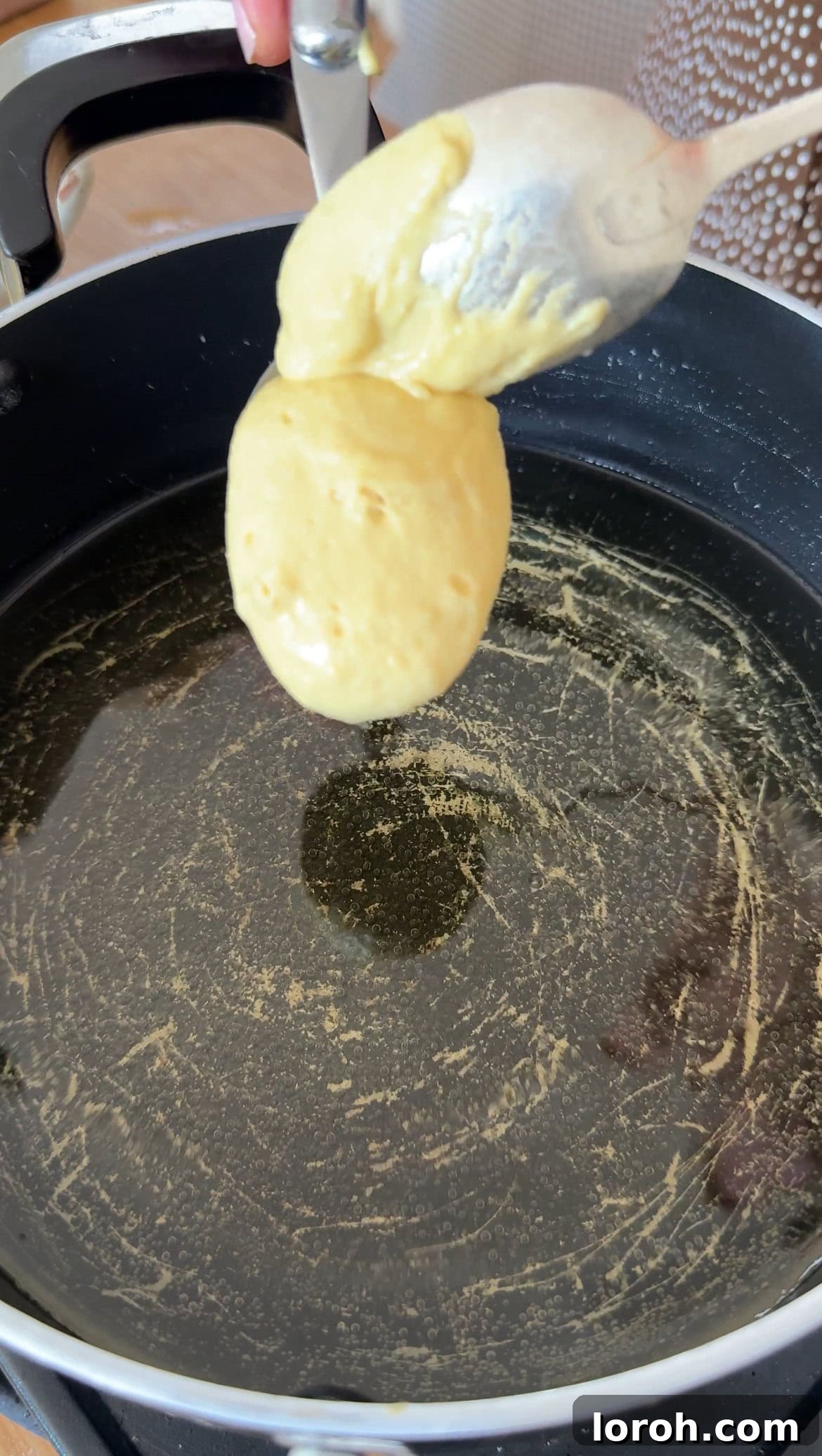 Pillowy Italian Sfingi Doughnuts 6 Spoonfuls of Sfingi batter being carefully dropped into shimmering hot oil in a pan.