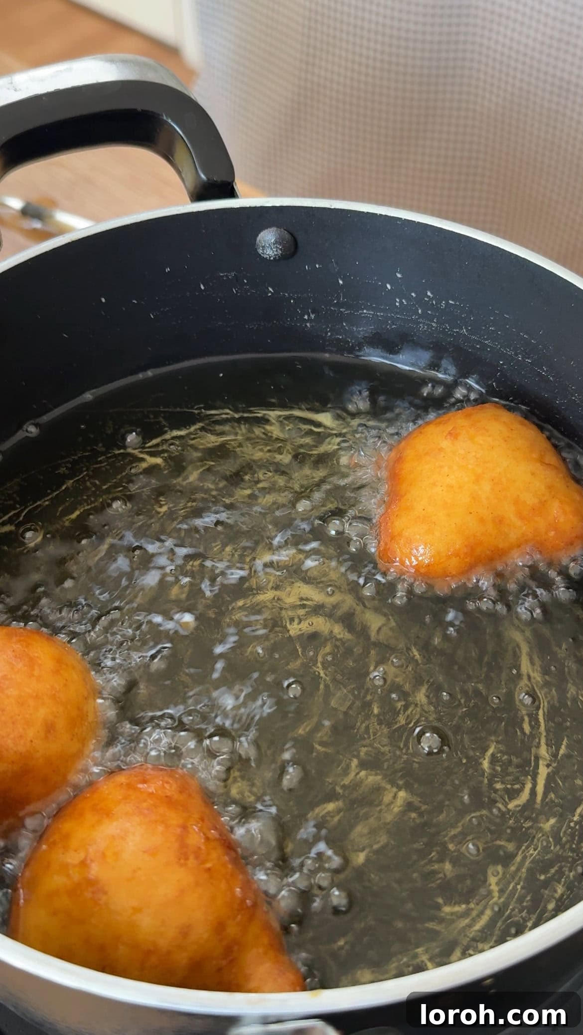 Pillowy Italian Sfingi Doughnuts 8 Golden, perfectly puffed Sfingi being removed from the frying oil with a slotted spoon.