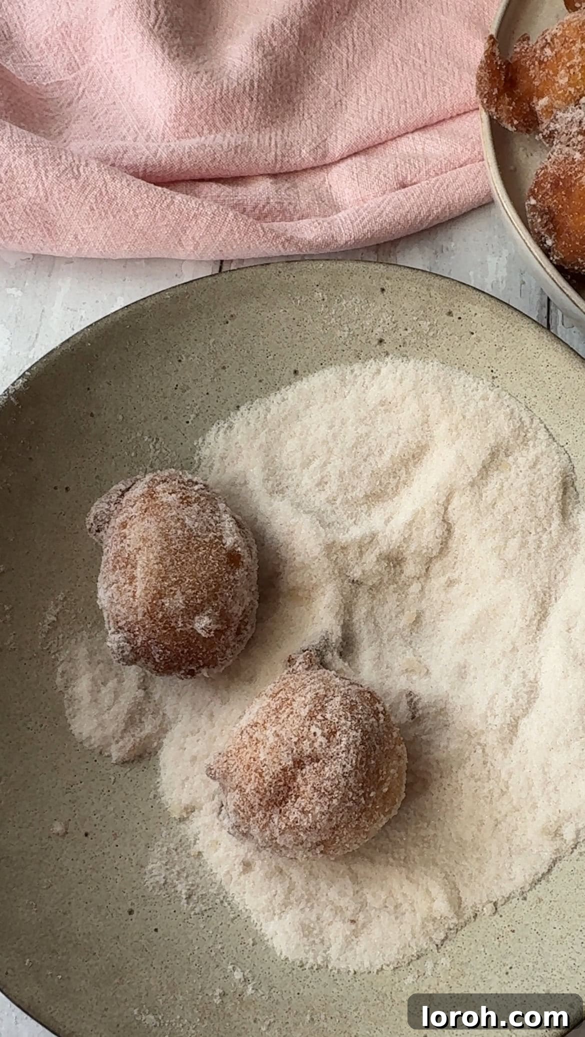 Pillowy Italian Sfingi Doughnuts 9 Warm Sfingi doughnuts being gently tossed and rolled in cinnamon sugar in a bowl.