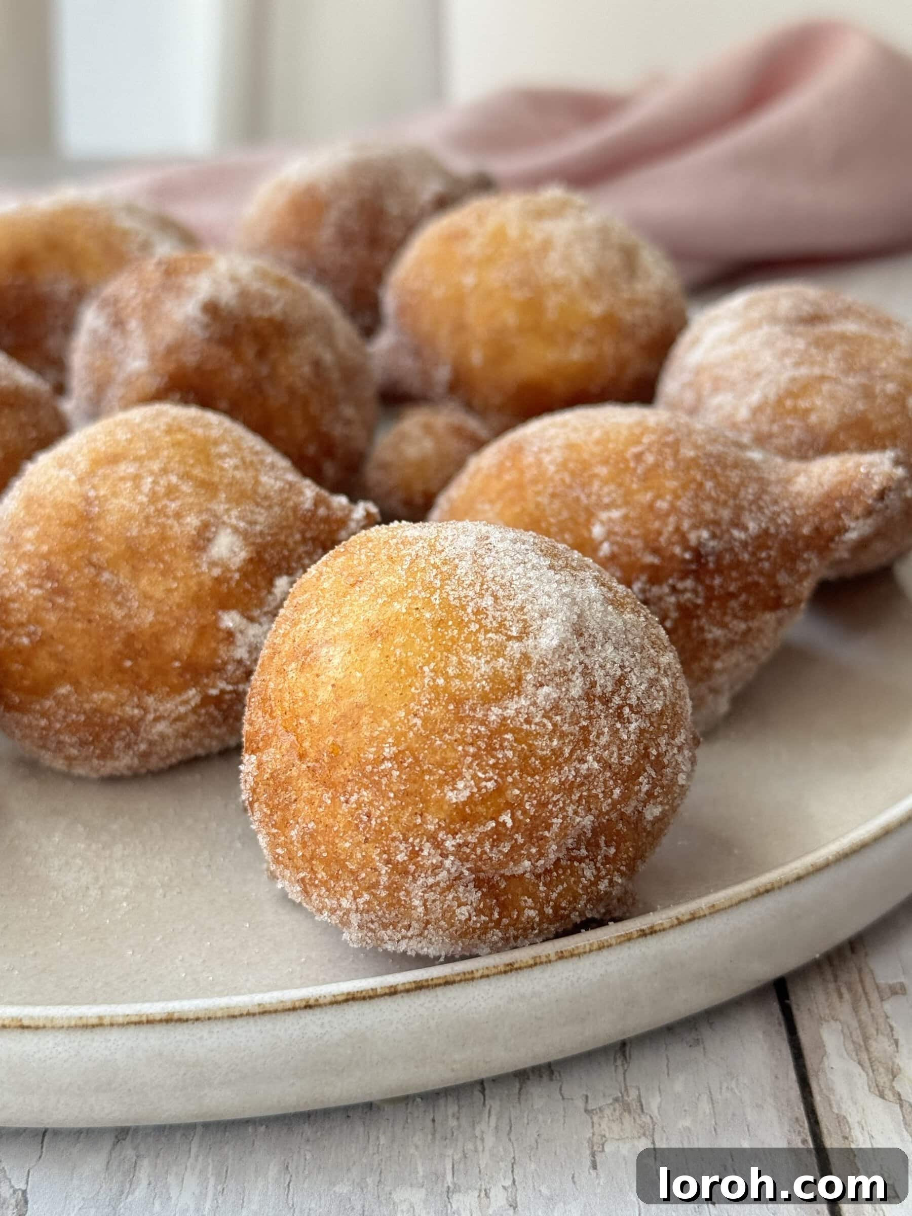 Pillowy Italian Sfingi Doughnuts 10 A beautifully arranged plate of freshly made Sfingi doughnuts, coated in sugar, ready for serving.