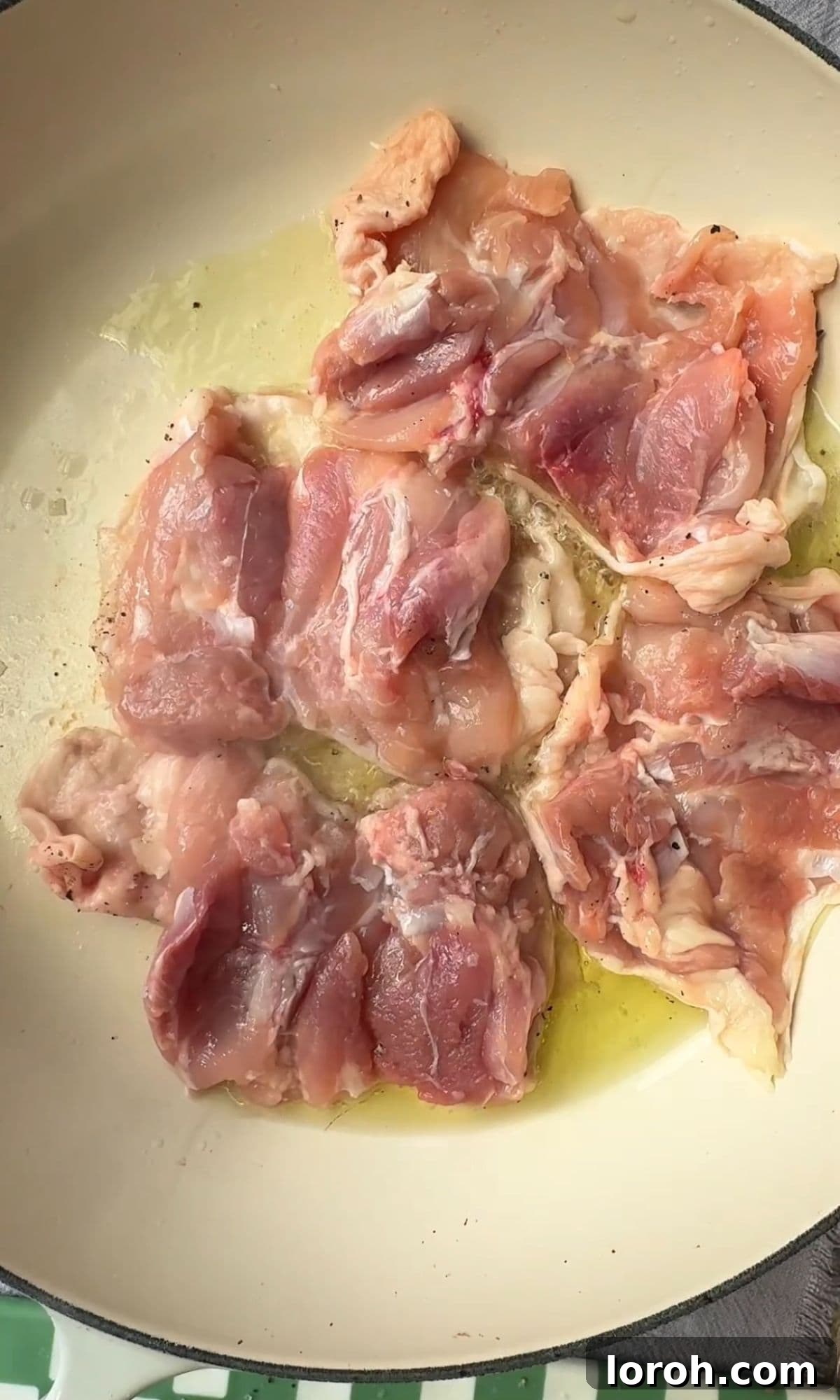 Frying chicken thighs in a large pan.