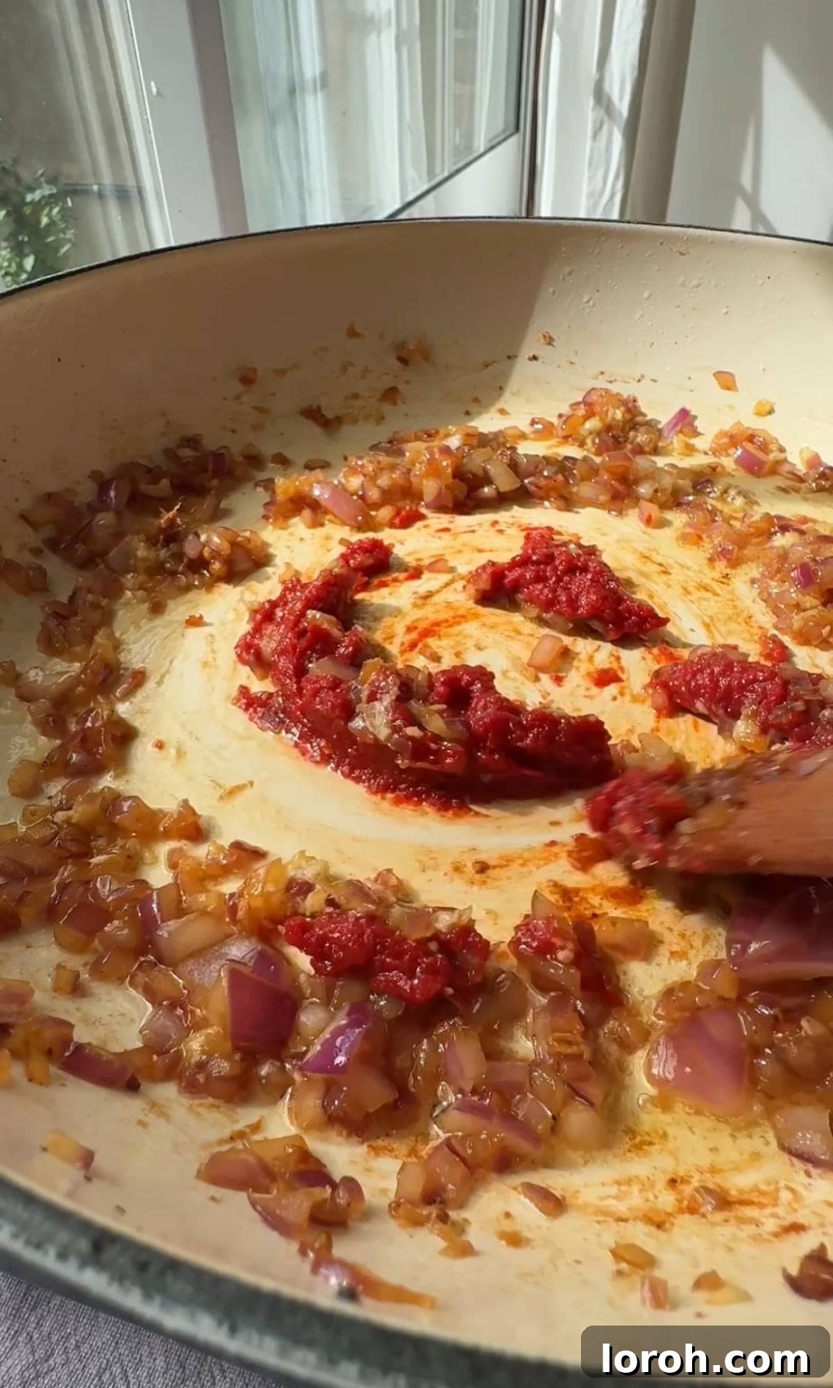 Adding tomato puree to the cooked onions and garlic.
