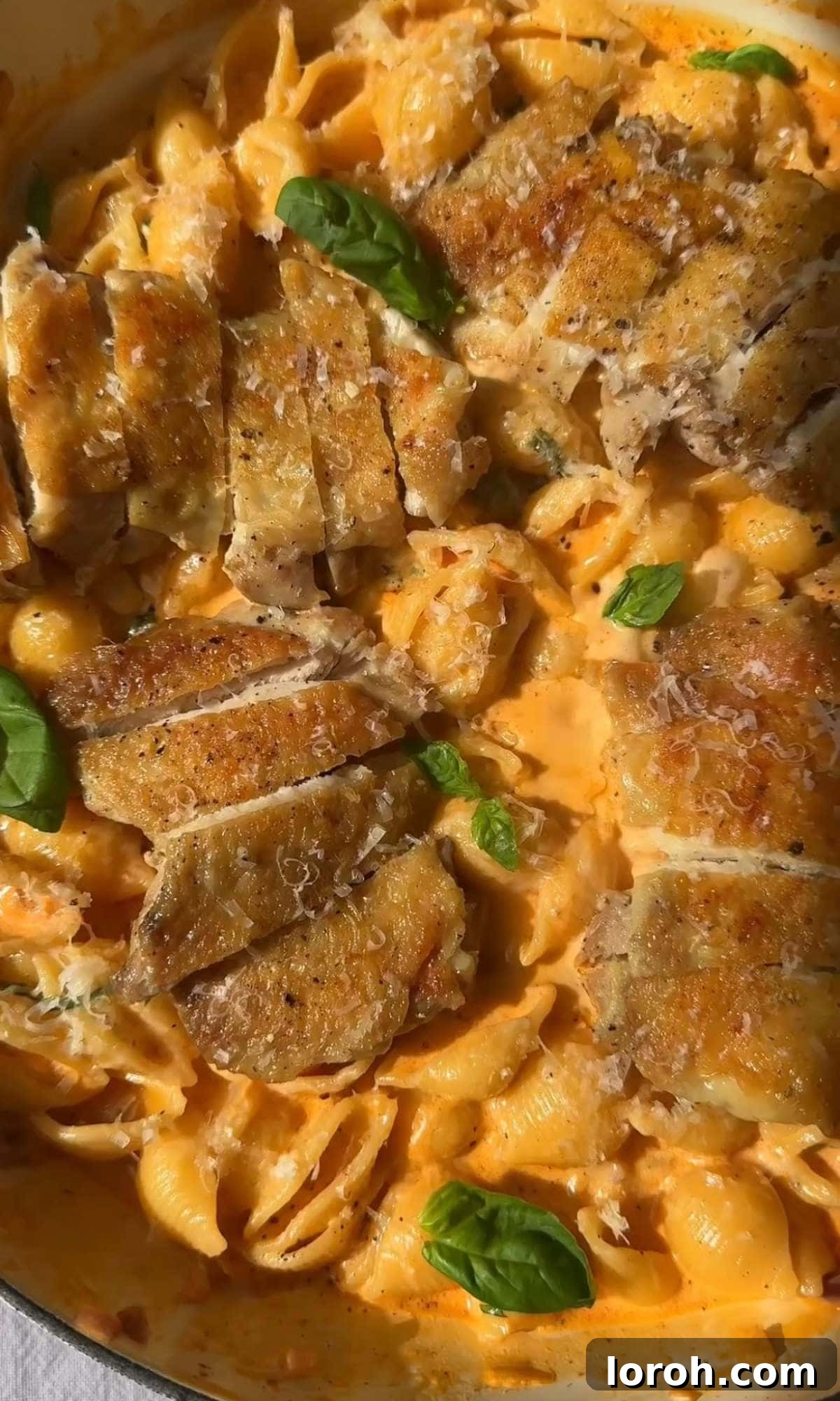 Adding sliced chicken to the finished parmesan garlic pasta.