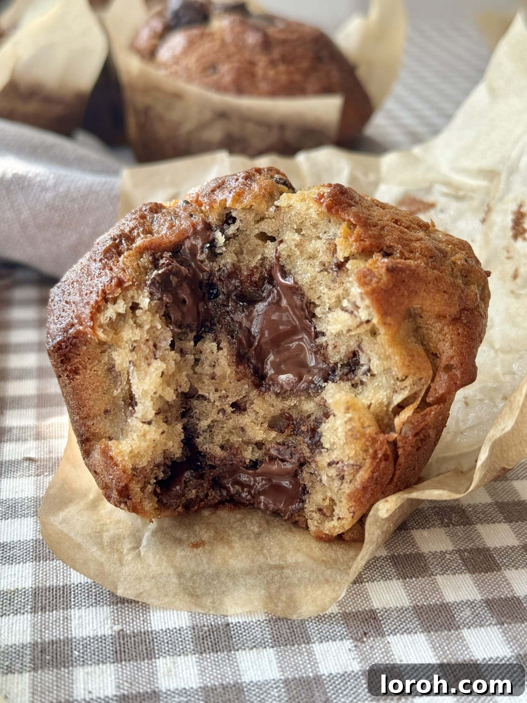 Cross section of a perfectly baked banana chocolate chunk muffin, revealing melty chocolate.