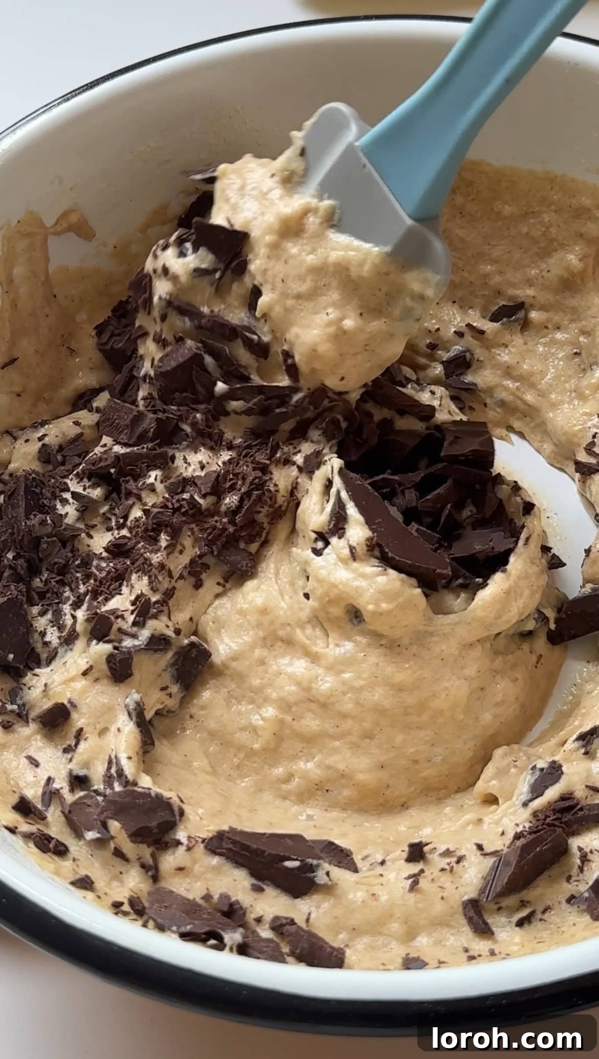 Folding chocolate chunks into the muffin batter.