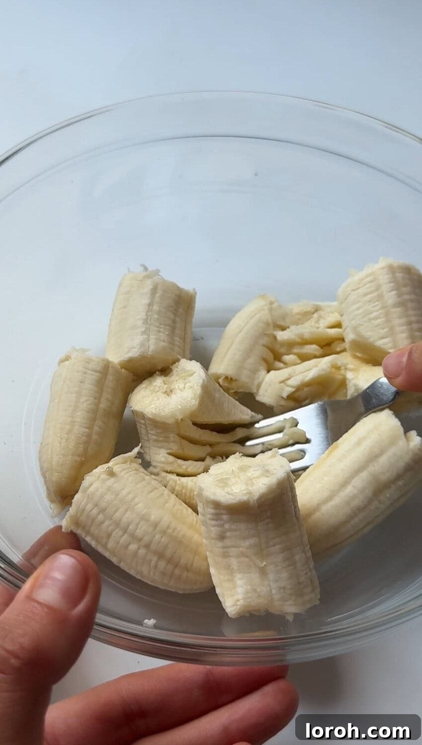 Mashing ripe bananas in a bowl.
