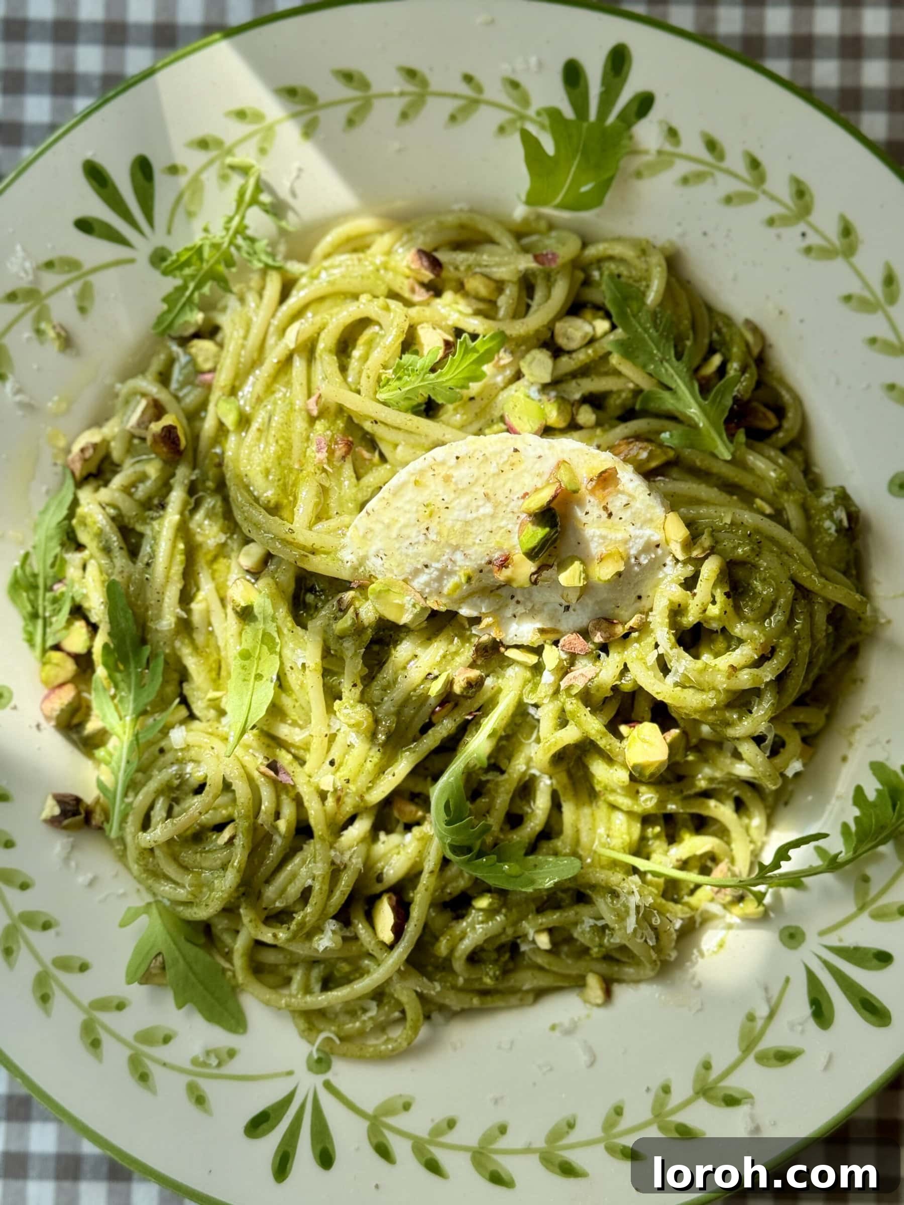 A vibrant bowl of Pistachio Pesto Pasta, rich green pesto clinging to spaghetti, garnished with fresh pistachios.