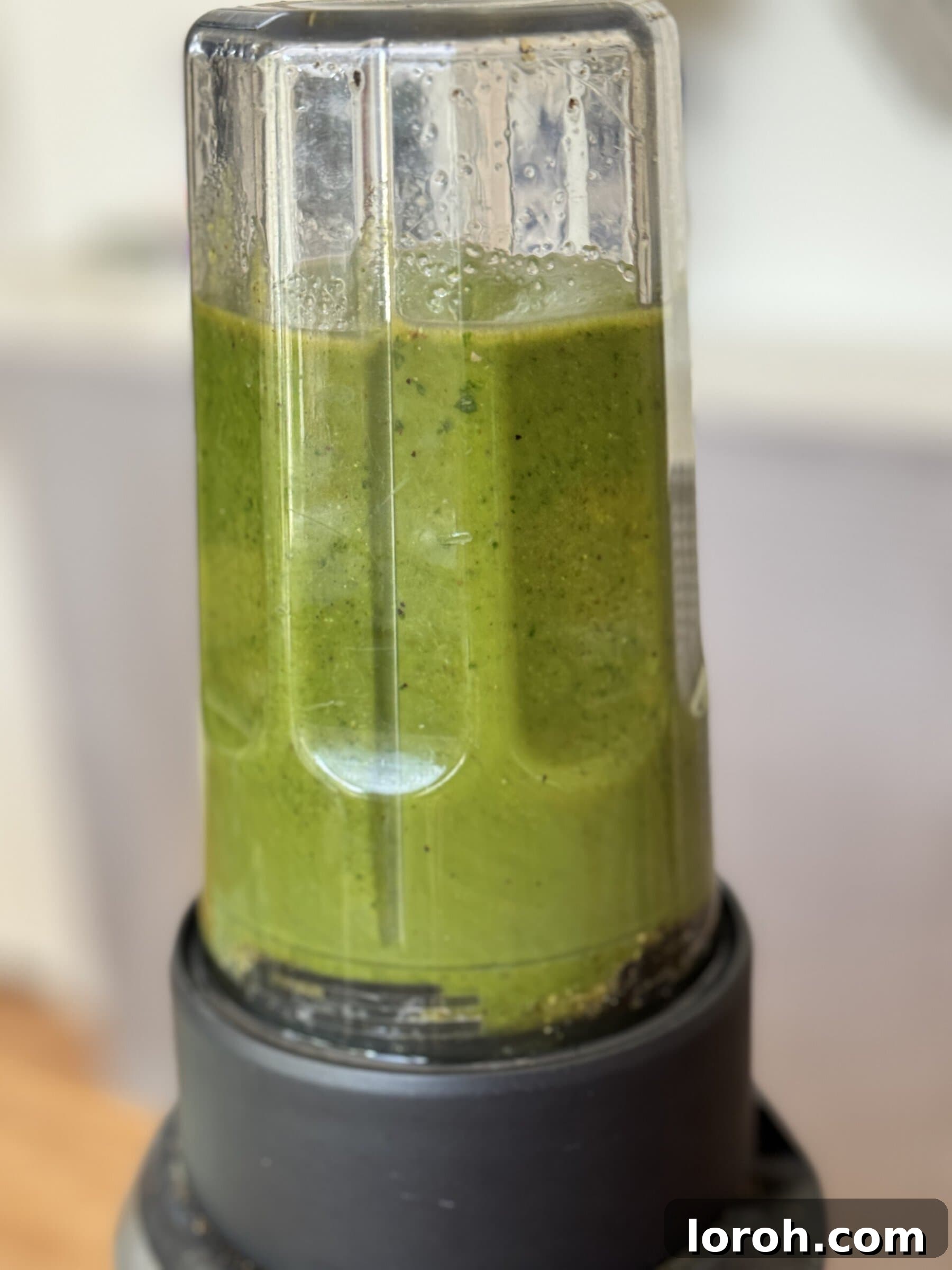 Pistachio pesto blending in a food processor, creating a smooth green sauce.
