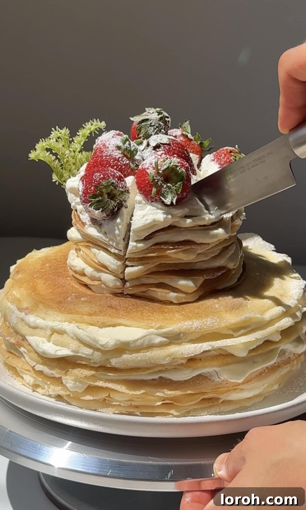 Slicing a chilled Strawberry Mille Crêpe Cake cleanly into individual servings.