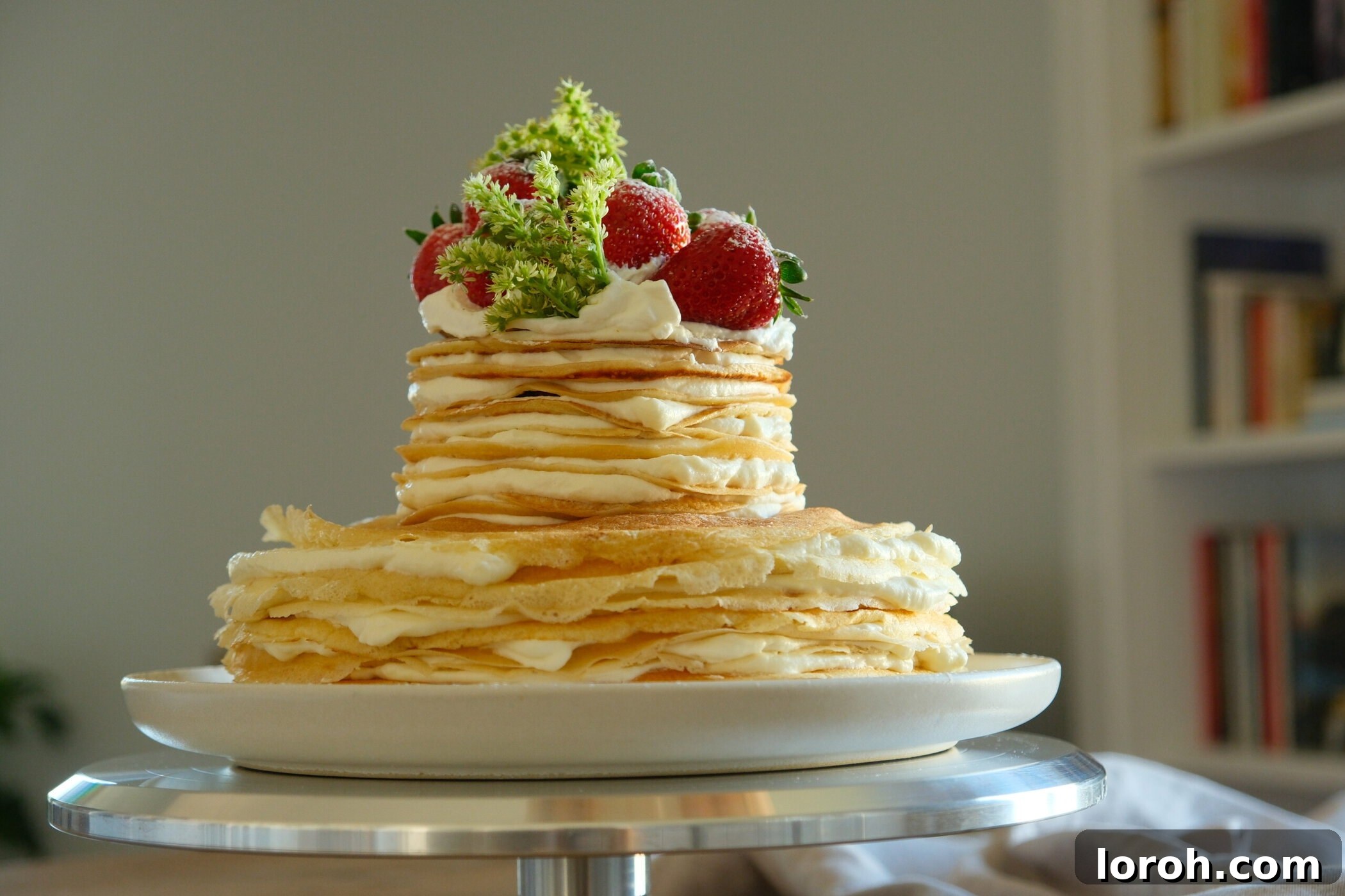 Beautiful side angle view of a tall Strawberry Mille Crêpe Cake, showing off its many layers.