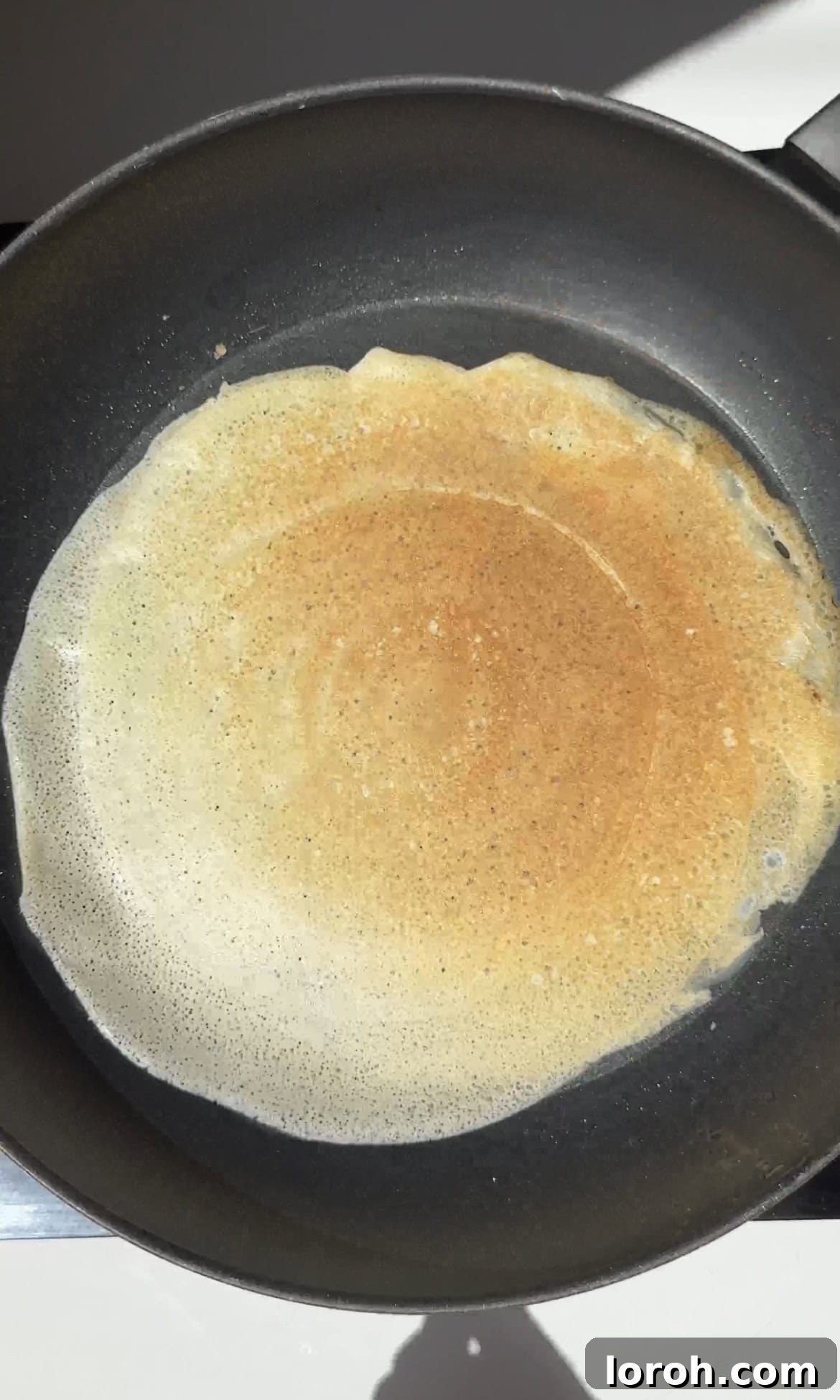 Stacking freshly fried crêpes on a plate as they finish cooking.