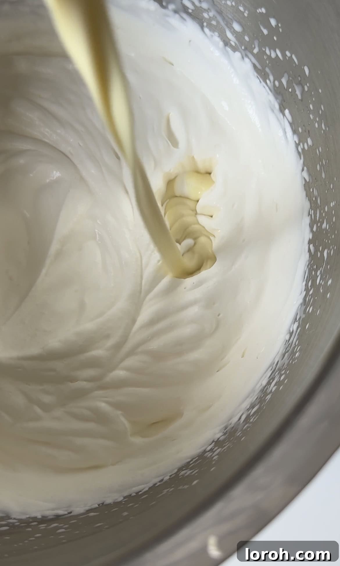 Gently folding cooled melted white chocolate into softly whipped double cream.
