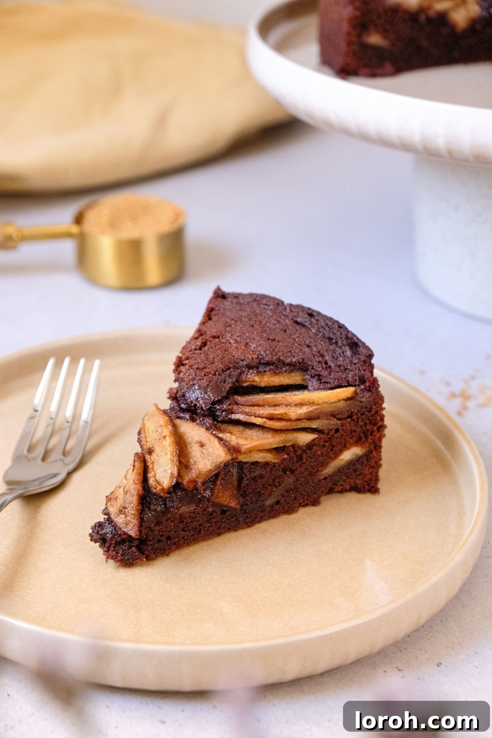 Decadent Chocolate Pear Dream 2 A perfectly sliced chocolate and pear cake resting on a beige plate, showcasing its rich texture and layered fruit.