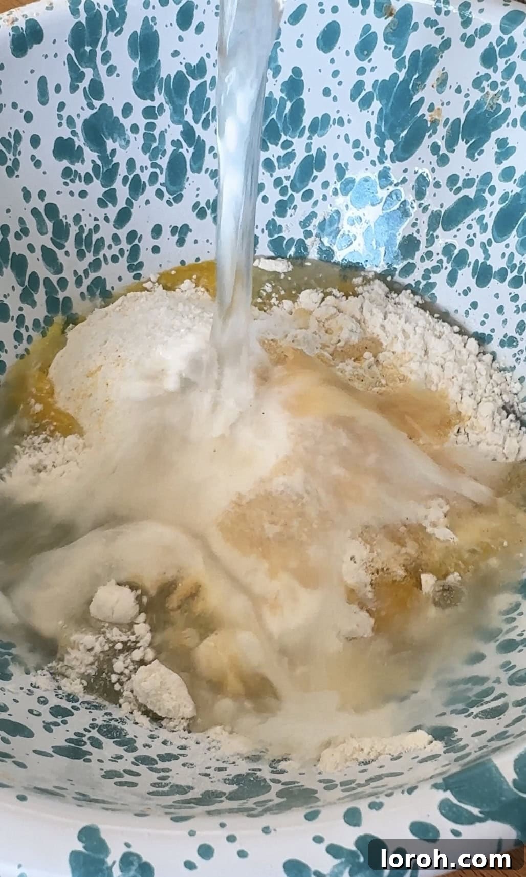 Golden Crispy Panko Shrimp 4 Adding water to a bowl containing eggs and flour to create the batter.
