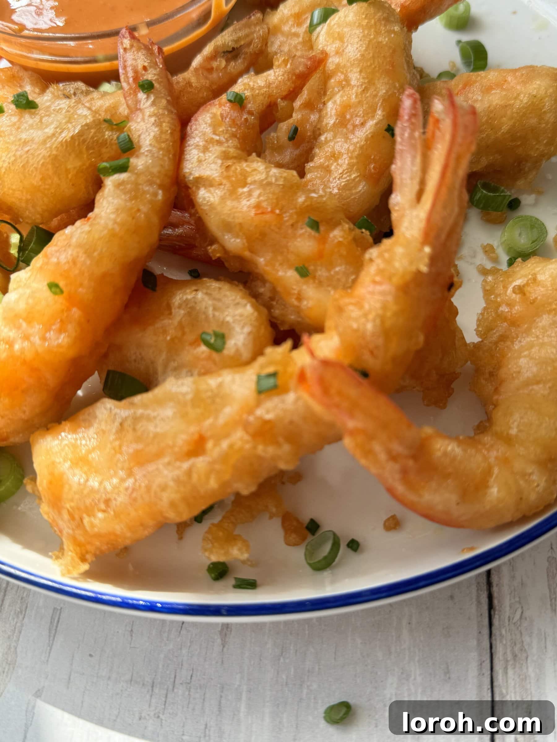 Golden Crispy Ebi Tempura 10 A beautifully arranged plate of Japanese shrimp tempura (Ebi Tempura) with dipping sauce.